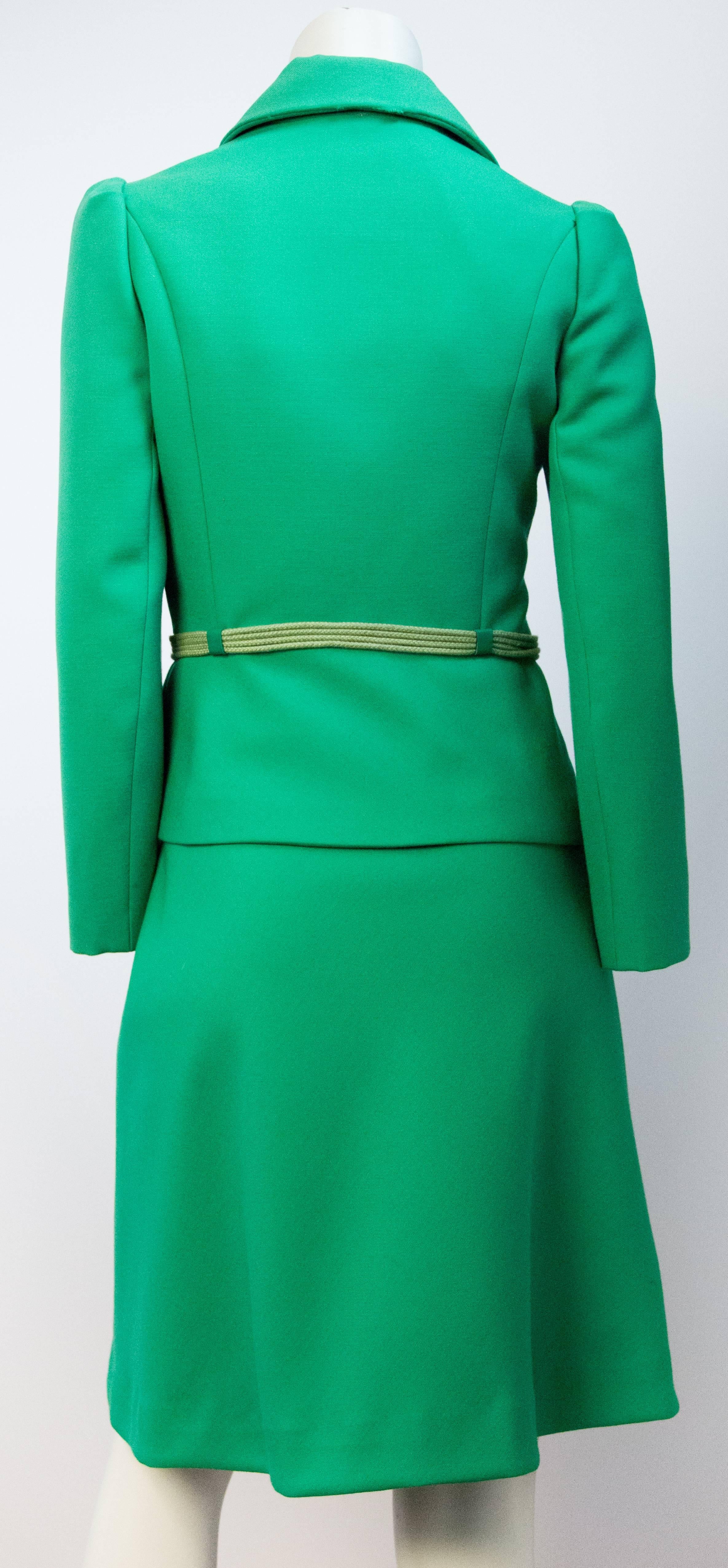 Late 60s fitted green skirt suit. Princess seam fitted jacket. Gold tone buttons on jacket. Green cord and leather belt. Jacket and skirt fully lined in green acetate. Side nylon zipper, and hook and eye closure on skirt. 

Measurements:
Jacket