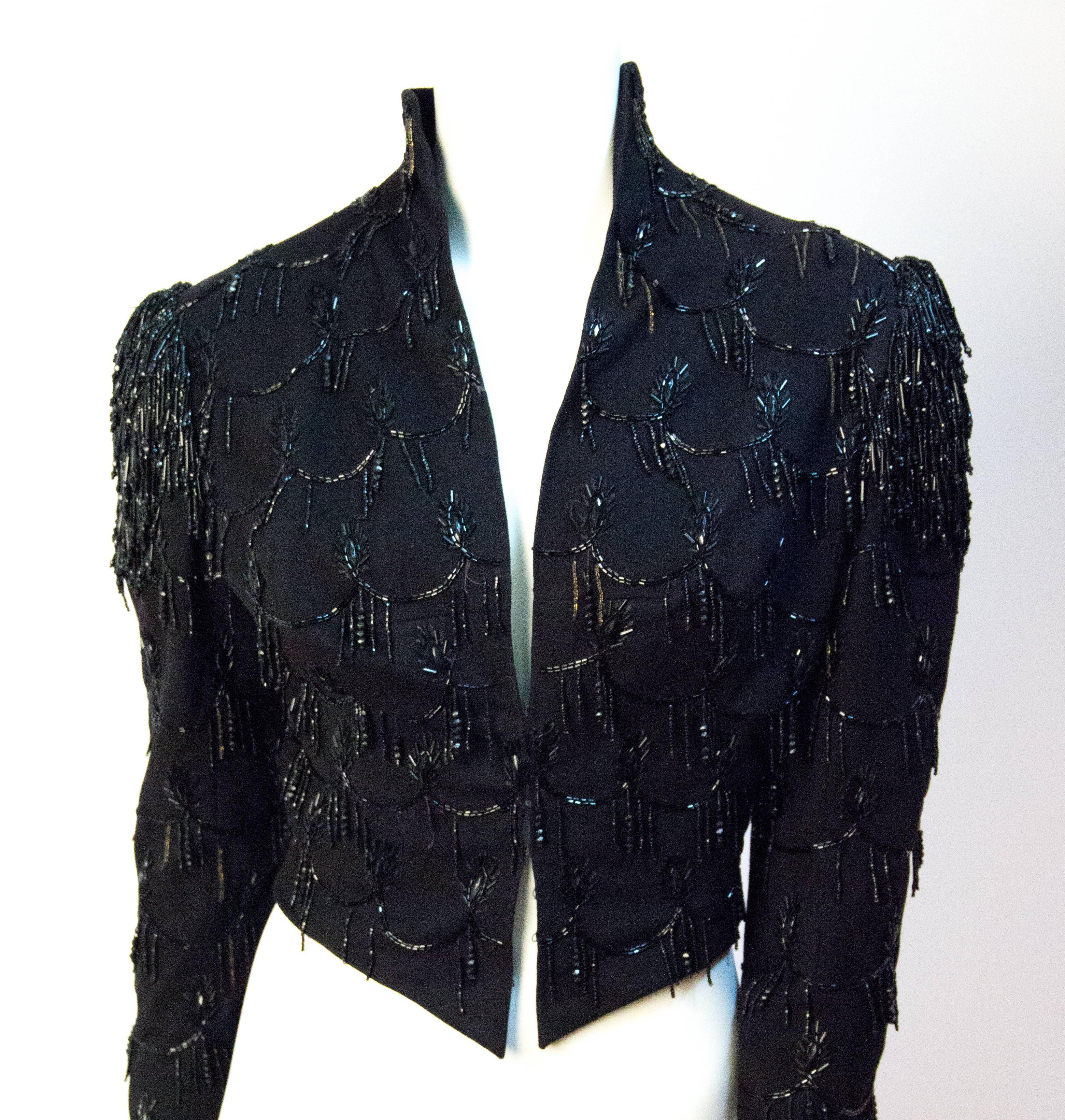 Victorian black wool jacket with jet bead embellishment. Beaded fringe shoulder detail. Lined in satin. Hook and eye closure. 