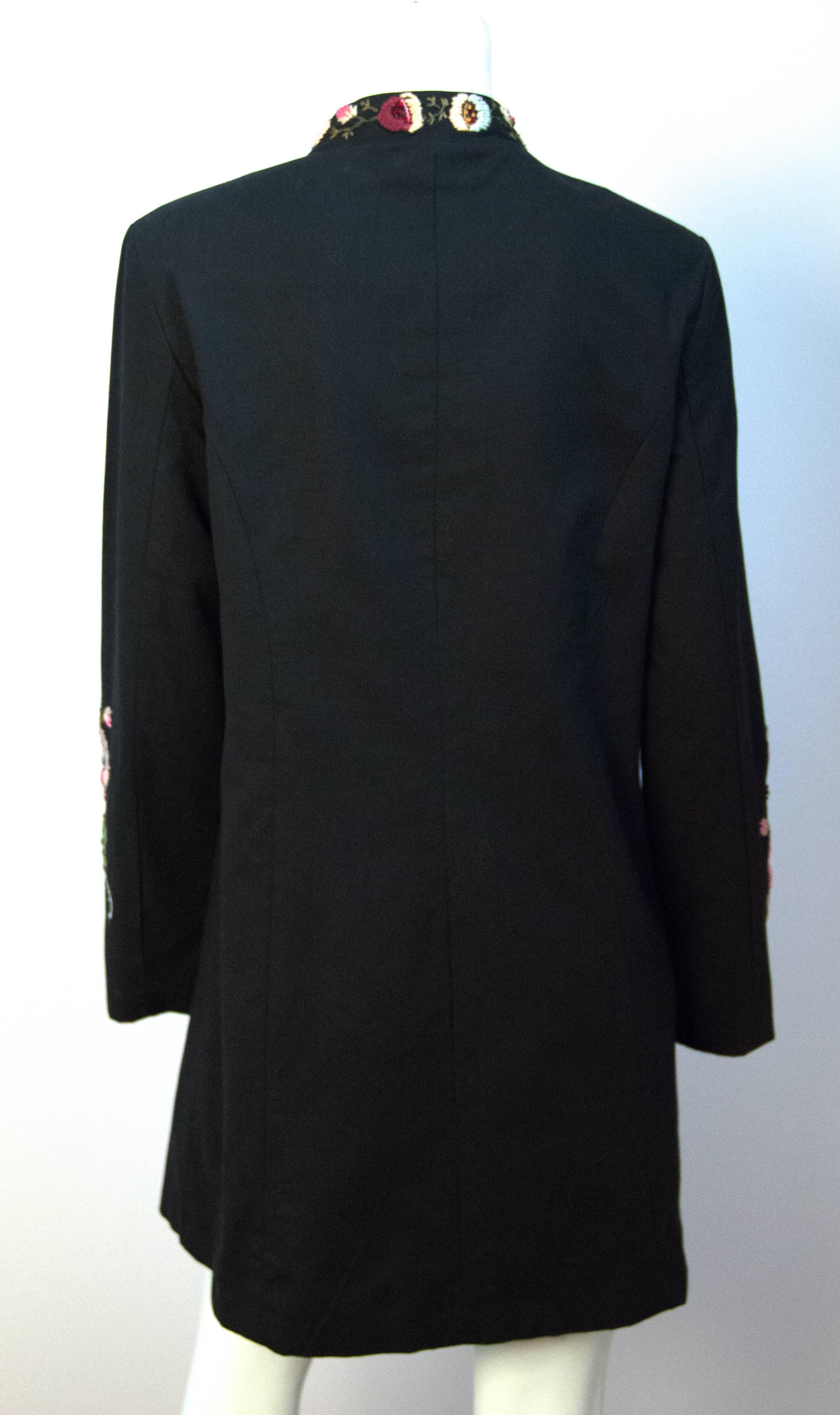 Giacca nera anni '70 con ricami floreali lungo il collo, le maniche e il davanti. Tasche invisibili. Chiusure con ganci e occhielli. Fodera in poliestere verde mare chiaro.

Questa giacca ha le seguenti misure:

Busto: 38 pollici
Lunghezza delle