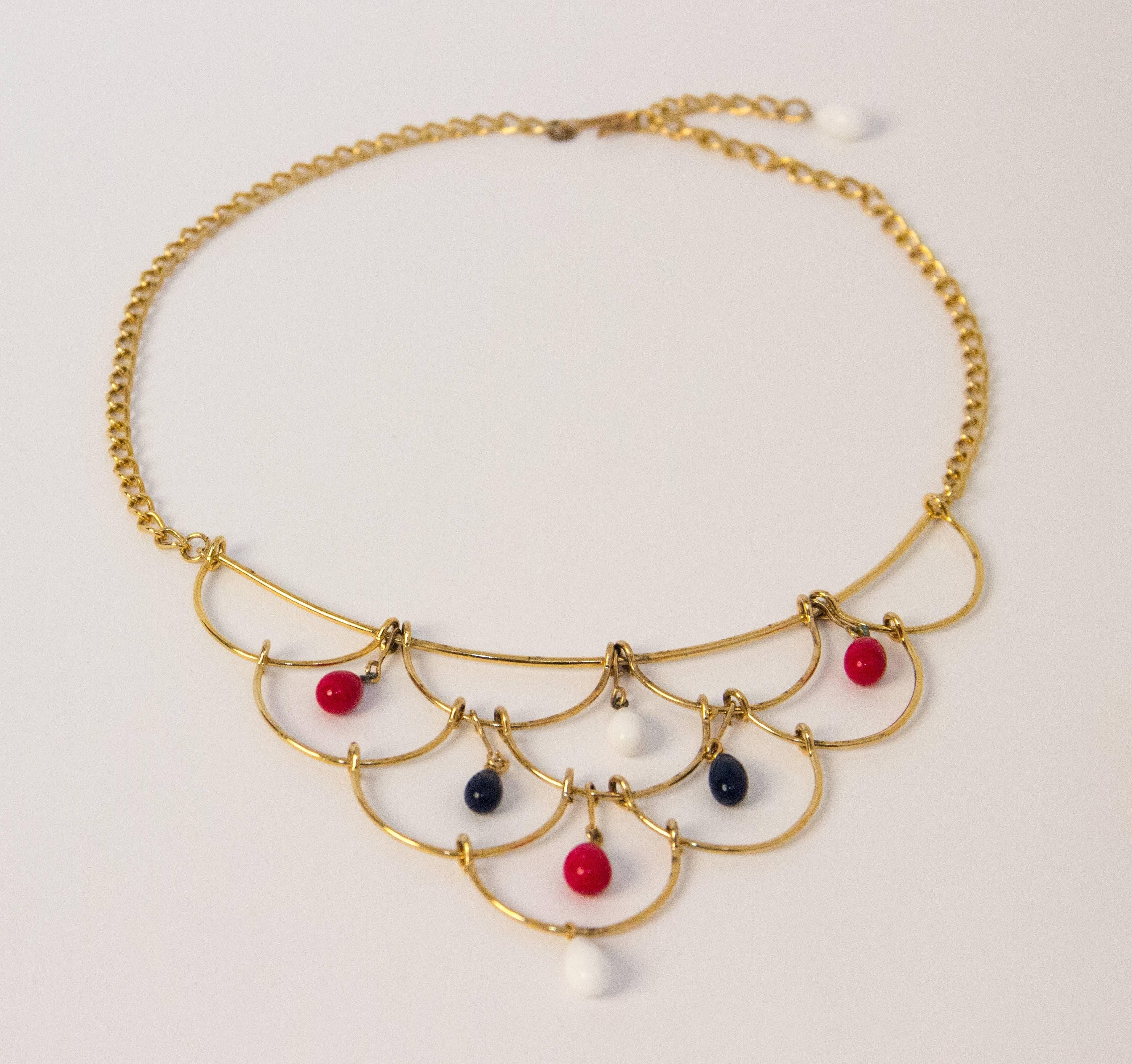 60s gold toned necklace and earring set with red, white and blue glass bead embellishments. Hook clasp on necklace. Clip on earrings.

Measurements:

Necklace: (chain is 6 1/4 inches long on each side = 12 1/2 total excluding plate) (Plate is