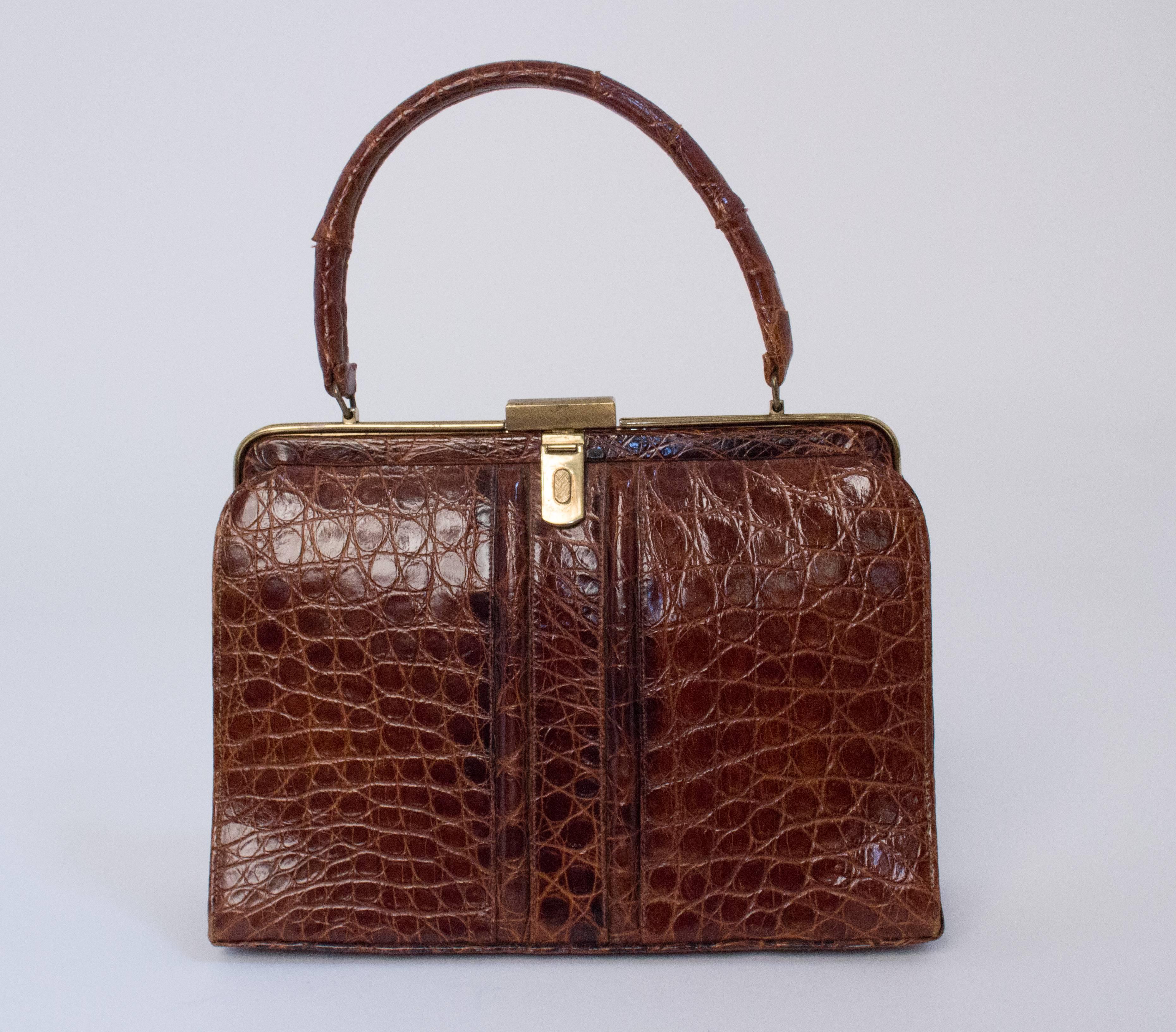 60s sienna brown alligator handbag. Gold tone hardware. Light tan leather interior. 3 interior pockets. I interior zip pocket. 

Measurements:
Body of bag: 9 3/4 x 7 1/4 inches 
Handle: 12 3/4 inches 