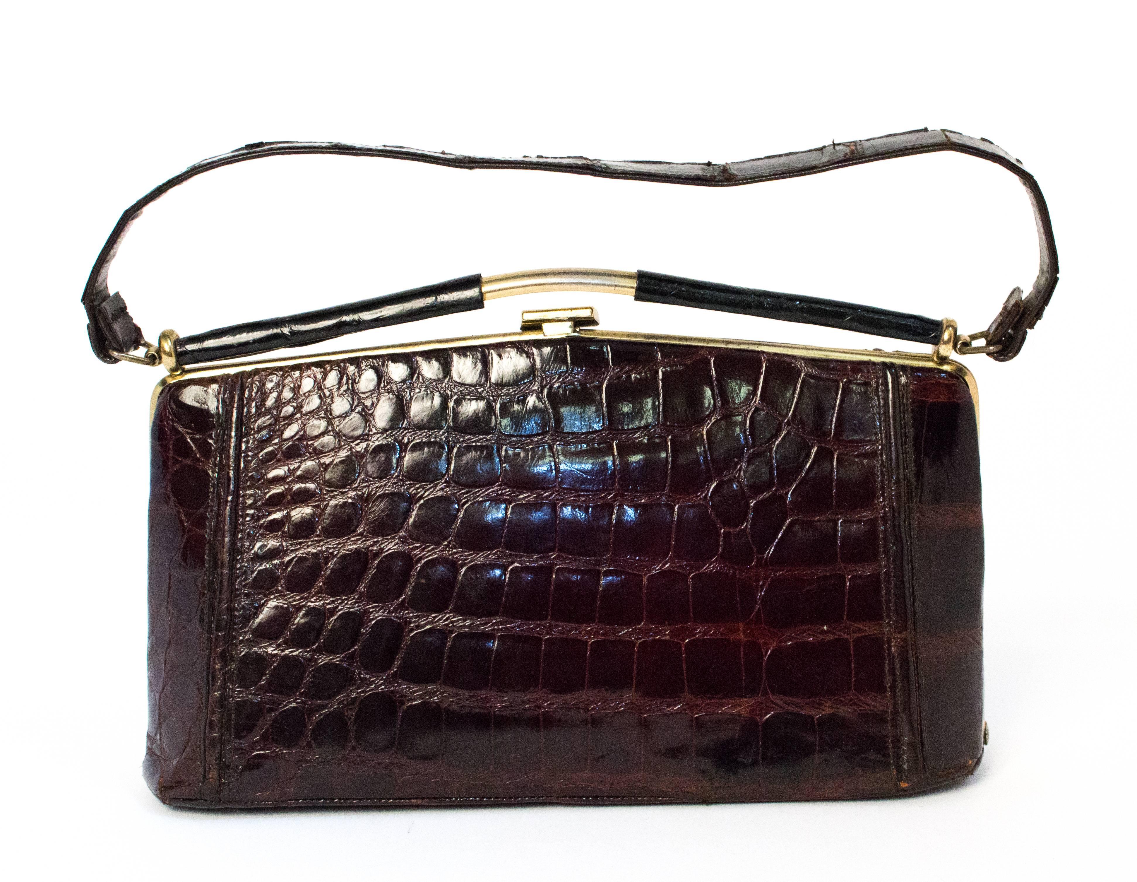 50s Brown Alligator Handbag. Alligator covered frame top. Gold toned hardware. One interior zip pocket. 

Measurements:
Body of bag: approx. 10 x 5 1/2 inches
Handle: 15 inches total