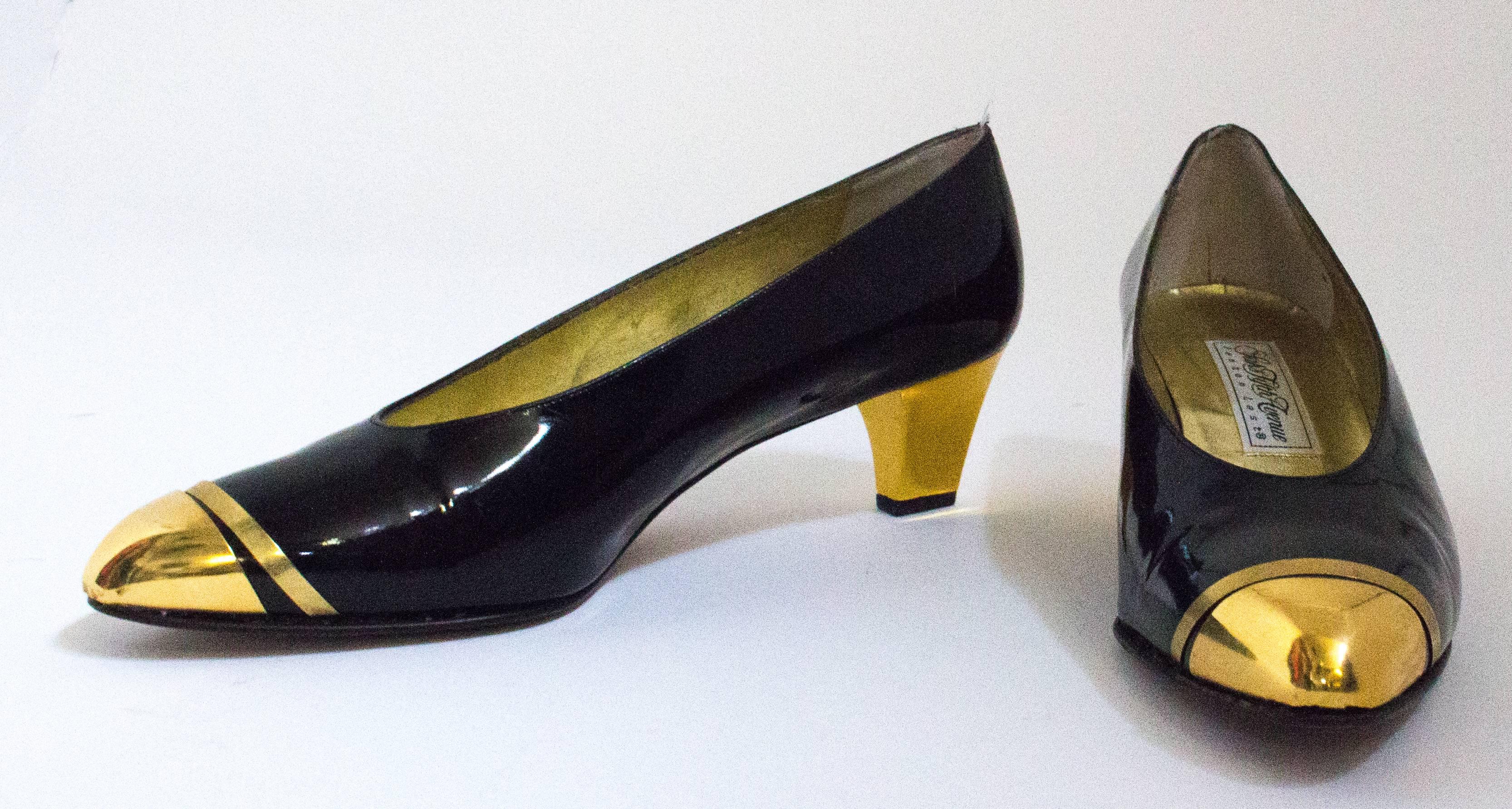 escarpins des années 80 en cuir verni noir avec cpas d'orteil et couvre-talon en métal doré. Semelles en cuir. Fabriquées en Italie. 

Mesures :

Semelle intérieure : 9 3/4 pouces
Paume du pied : 3 pouces 
Talon : 2 1/2 pouces 