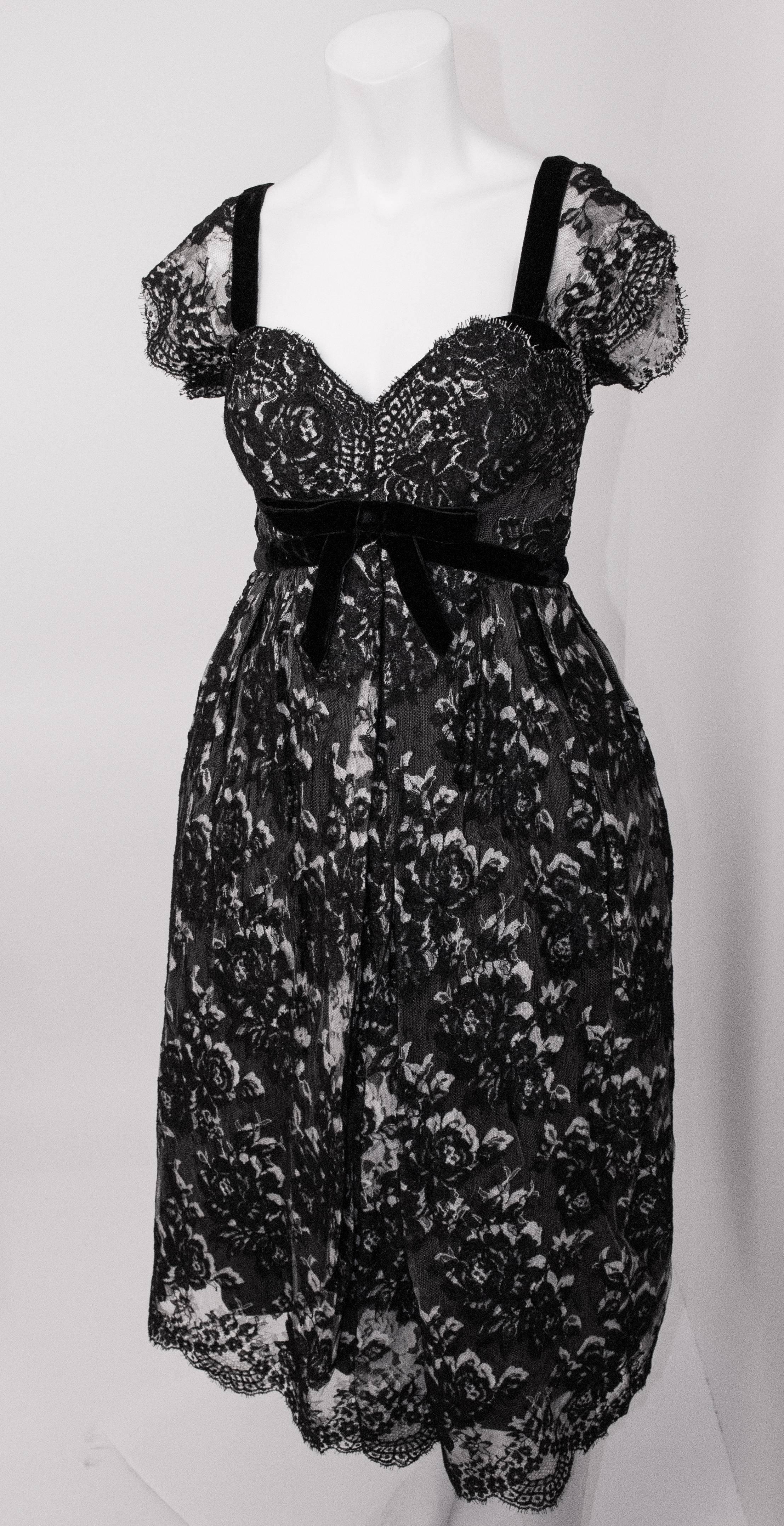 50s Black & White Lace Cocktail Dress. The black lace is layered over white lace. Velvet trim on bodice. Built in layered tulle petticoat. Grosgrain waist band hooks closed. Fully lined. 
