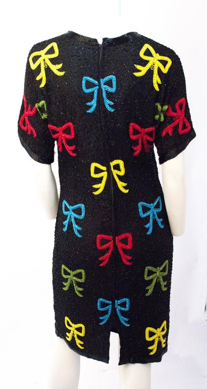 80s Black Beaded Dress with Red, Blue, Green & Yellow Bows. Fully lined. Zips up the back. 