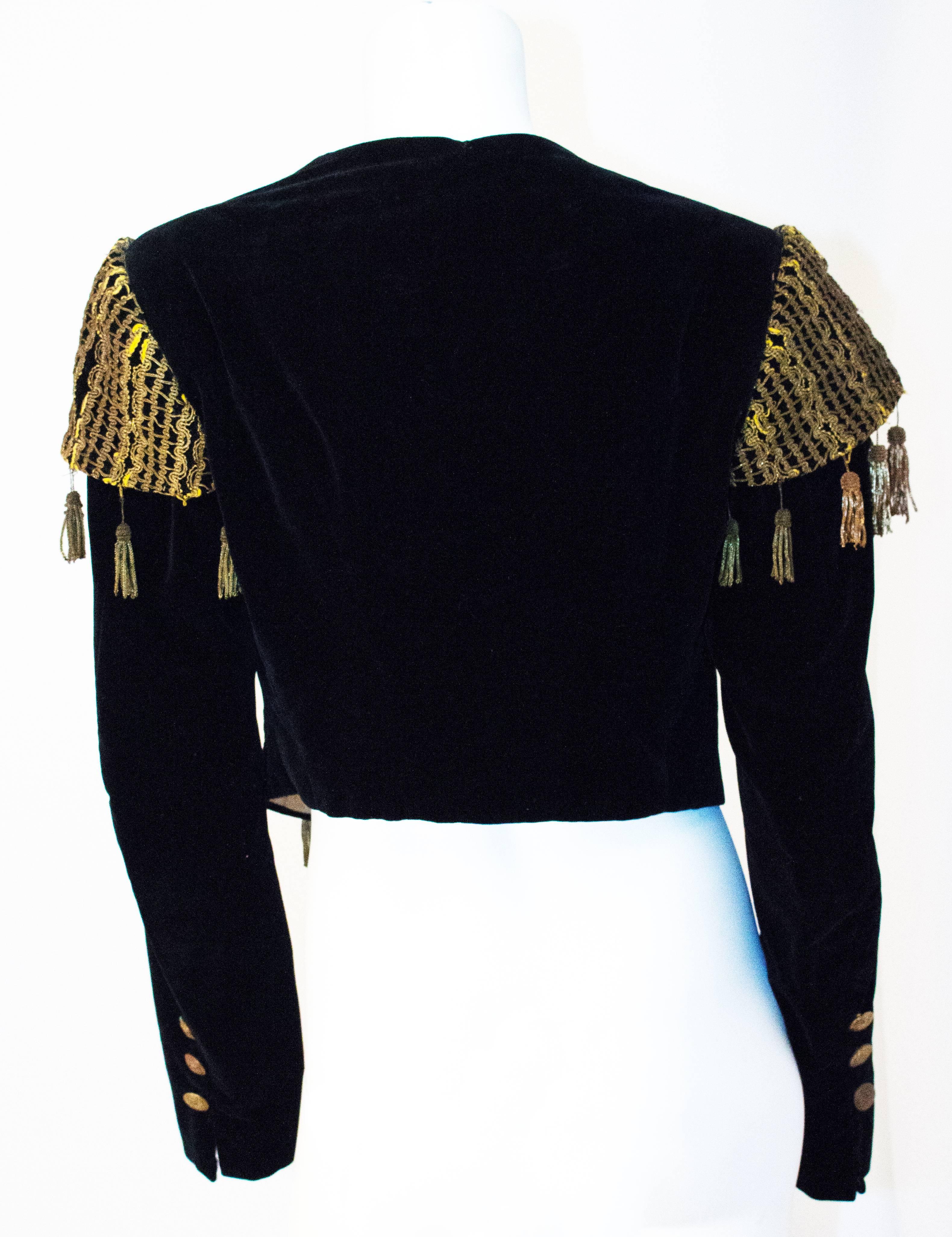 20s Black Velvet Bolero Jacket with Gold Metal Tassels & Embroidery. Lined in cotton. Not meant to close, worn open. Slight shoulder padding. Slightly longer in the front. 

Front Length: 18 1/2 inches
Back Length: 15 1/2 inches 

Shoulder