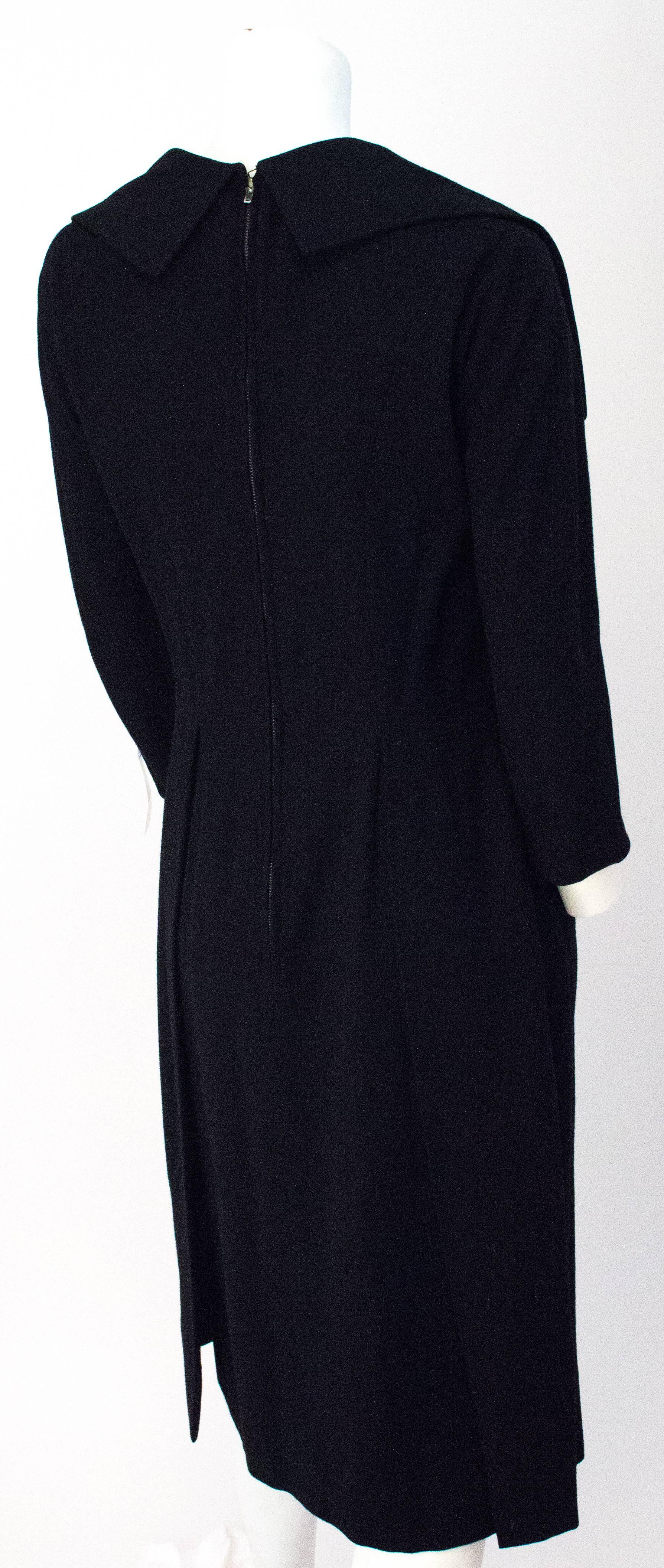 50s Black Wool V Neck 3/4 Sleeve Fitted Dress. Beaded buttons adorn the front collar detail. Metal zipper up the back. Fitted design. Fully lined. 

