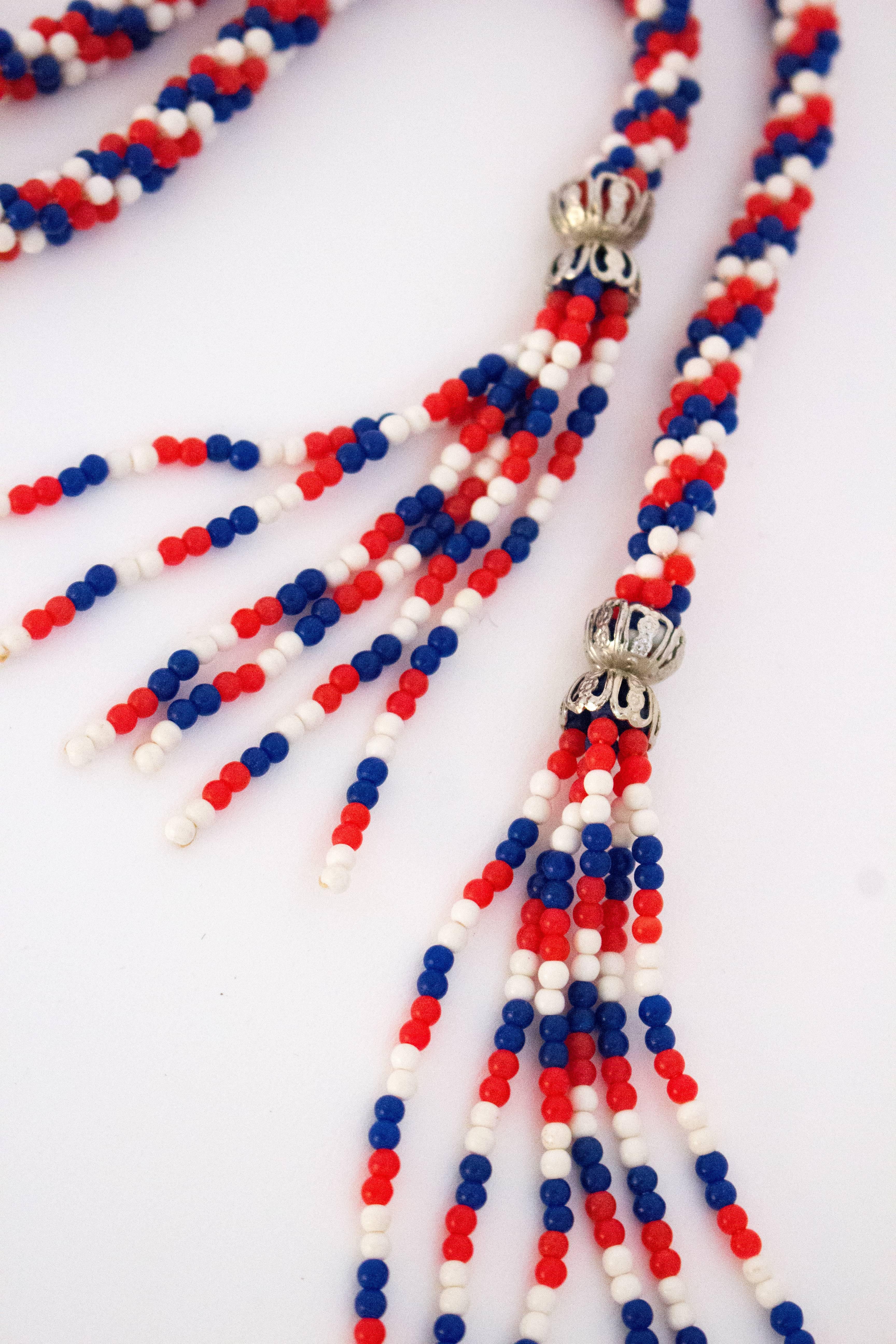 60s Red, White & Blue Rope Necklace. Silver toned bead ends at tops of tassels. Plastic beads. 

