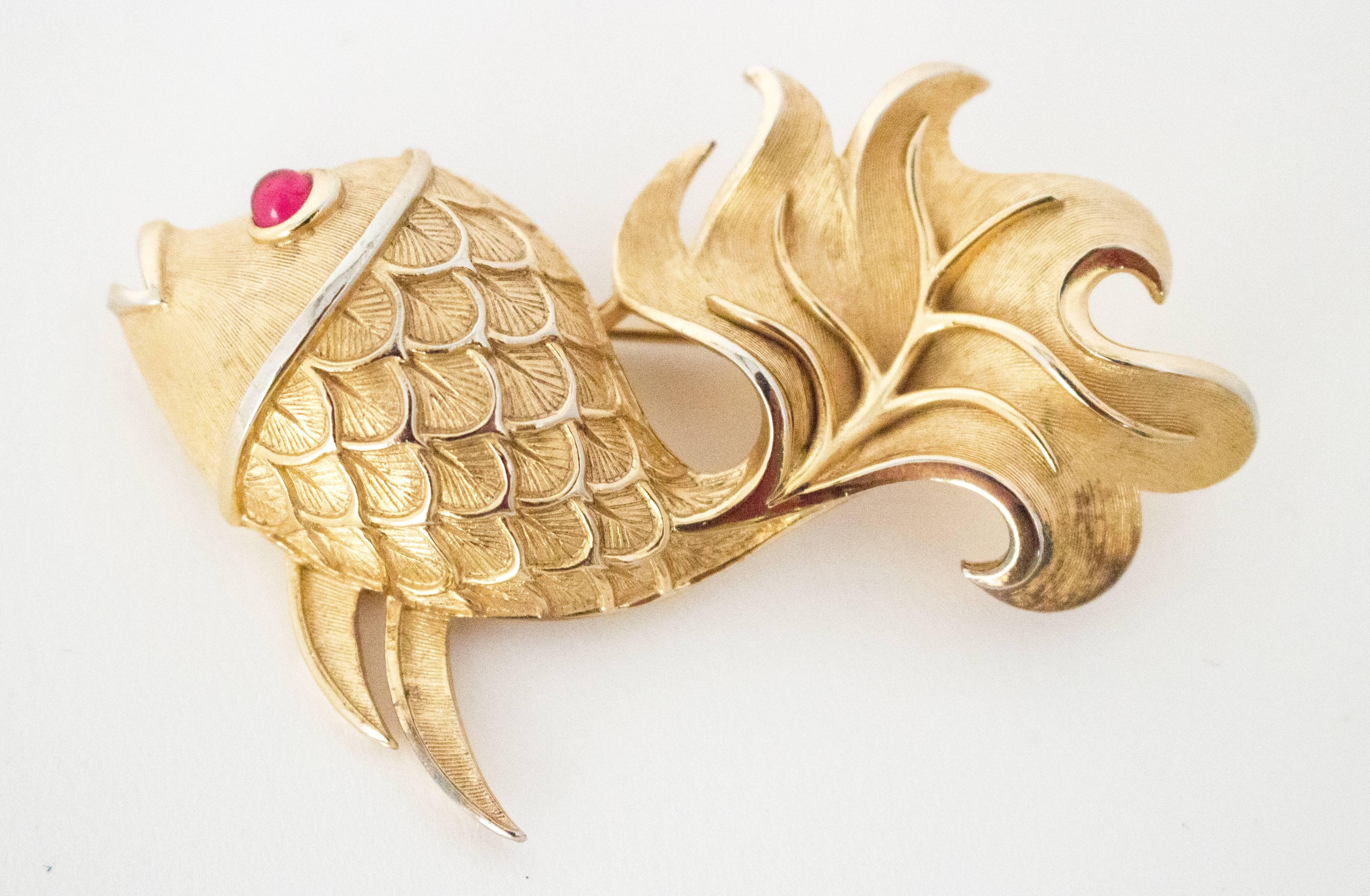 60s Trifari Gold Tone Fish Brooch. Brushed gold texture with smooth gold tone detailing. The eye is a faux pink ruby. 