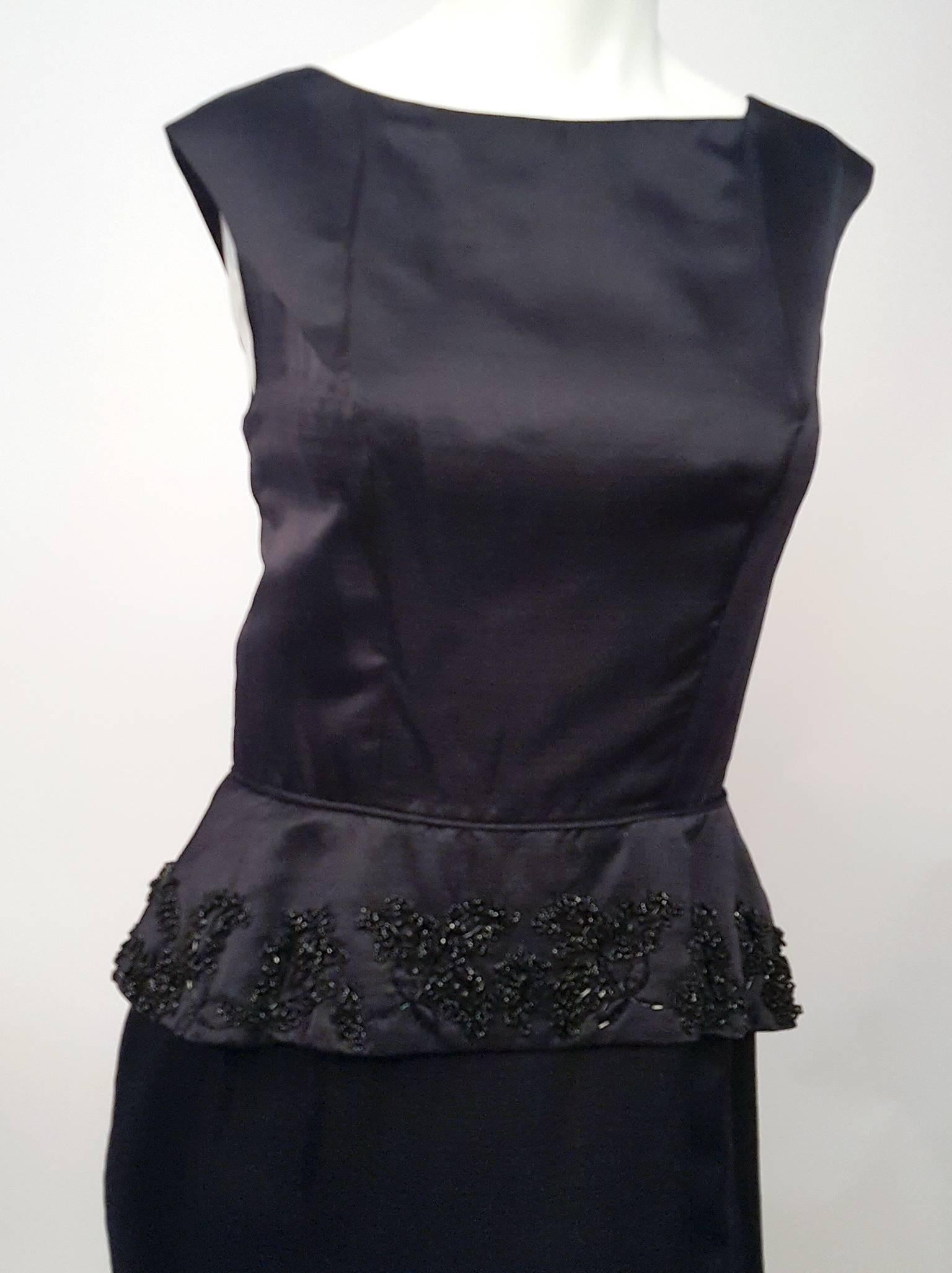 robe colonne noire perlée des années 60 avec péplum. Fermeture à glissière dans le dos.