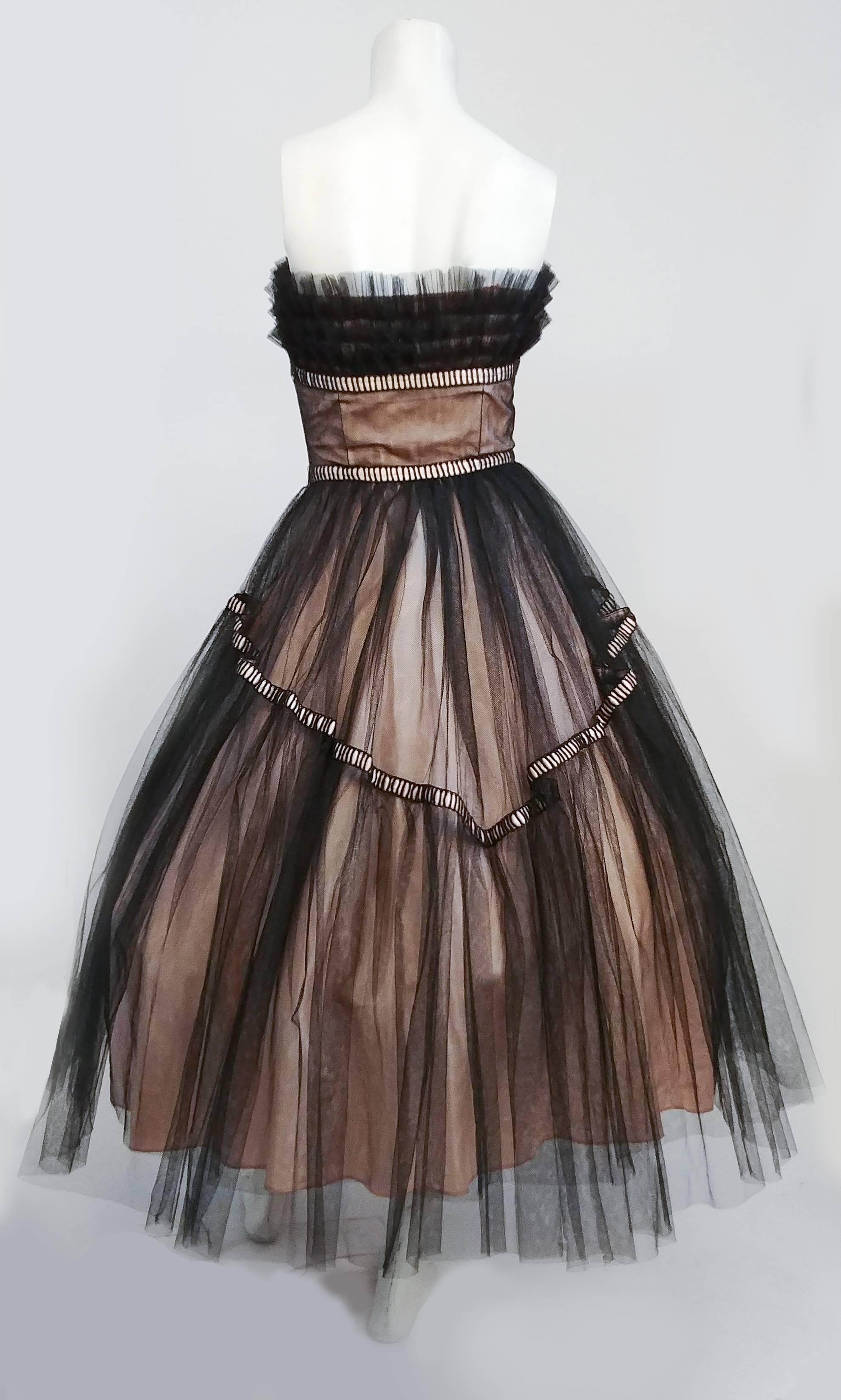 1950s Emma Domb Black and Pink Tulle Party Dress. Ruffled tulle bodice embellished with pearls. Ribbon embellishments. Two layers of black tulle over pink lining. Boned bodice. Worn over large petticoat in photo for full effect. 