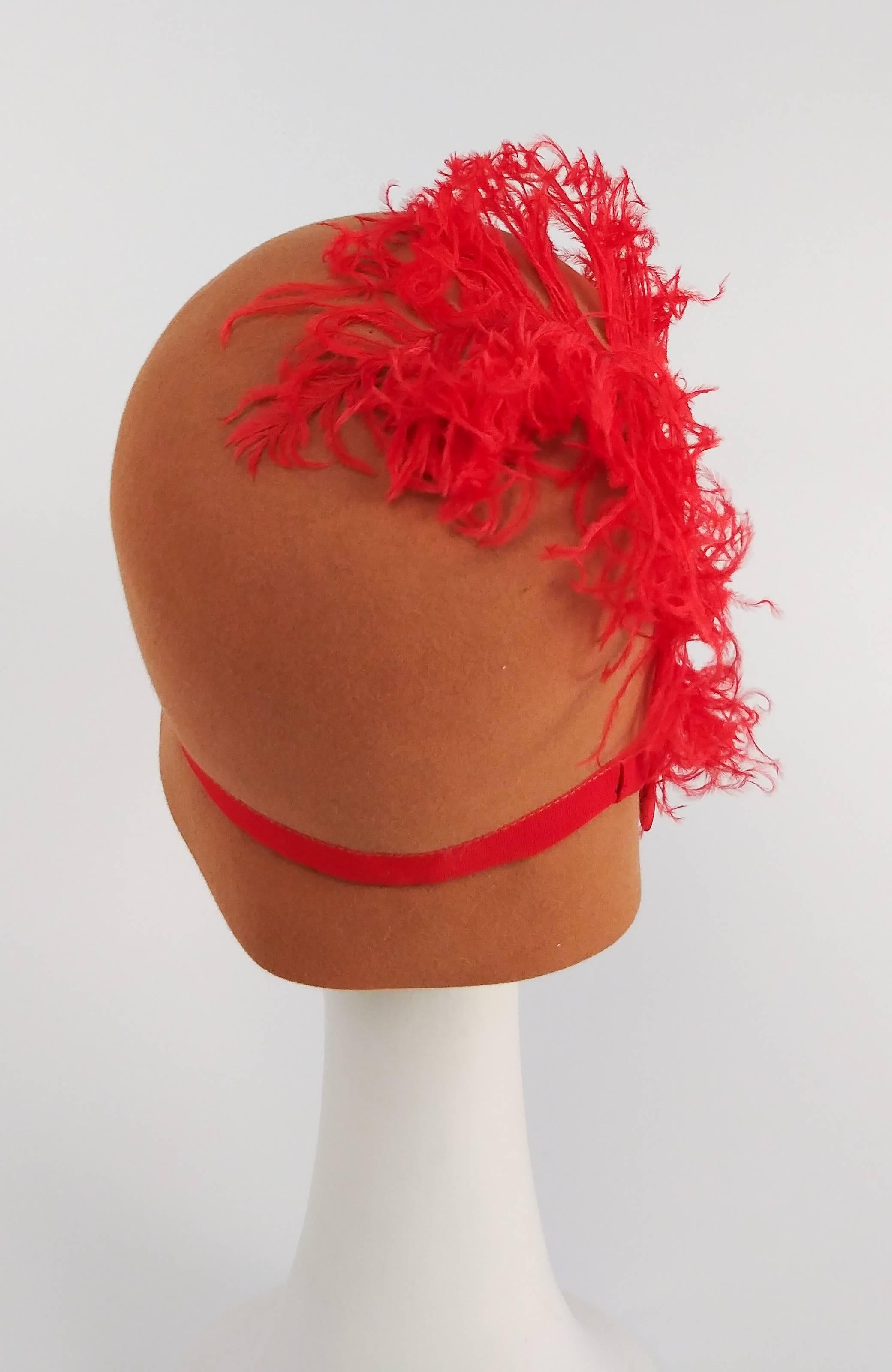 1960s Burnt Umber Cloche Hat w/ Red Feather. 1920s throwback hat from the 1960s. Hat dips down low on one side, trimmed with a red grosgrain bow and curled feather. 22