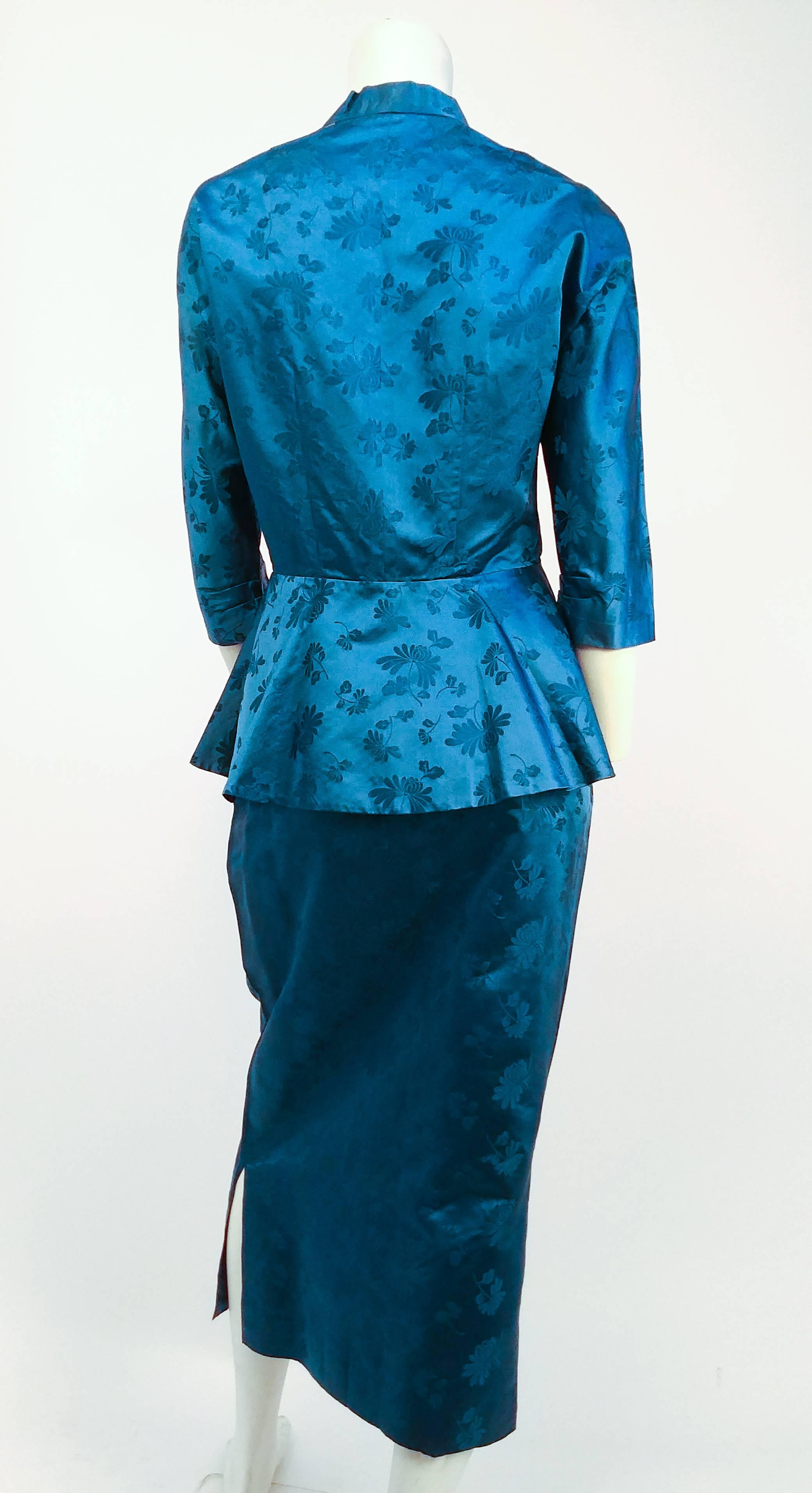 1950s Asian Silk Jacquard Skirt and Jacket Suit Set. Top fastens with snaps at neckline and frog at the waist. Flares at waist for classic peplum silhouette. Skirt has been altered to be longer, with additional contrast fabric added in between