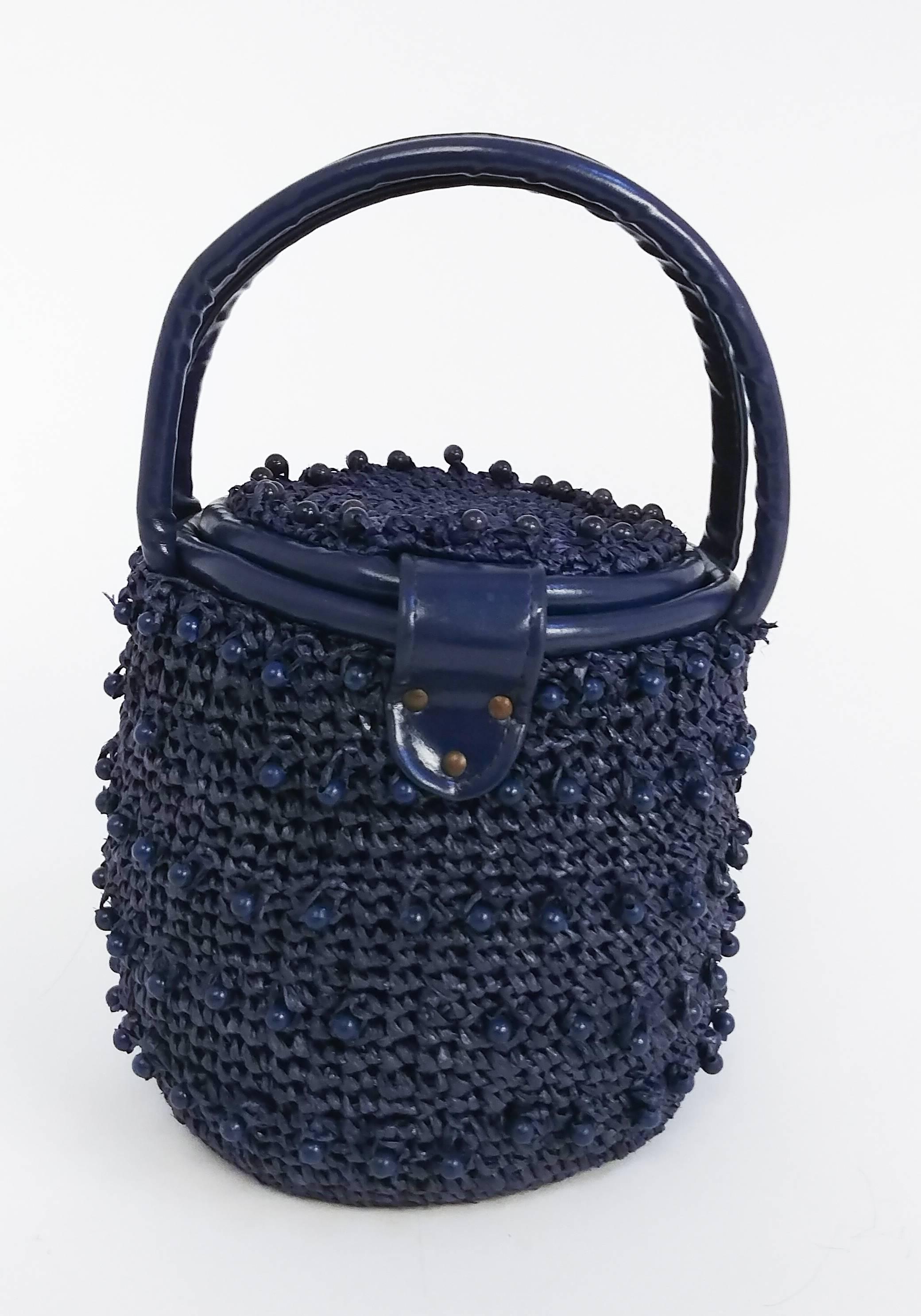 1960s Navy Raffia Woven Basket Purse. Wooden beads woven throughout. Leather straps, gold toned hardware. Clasp twists open and top flips up. Lined with cotton w/ one side inner pocket. 