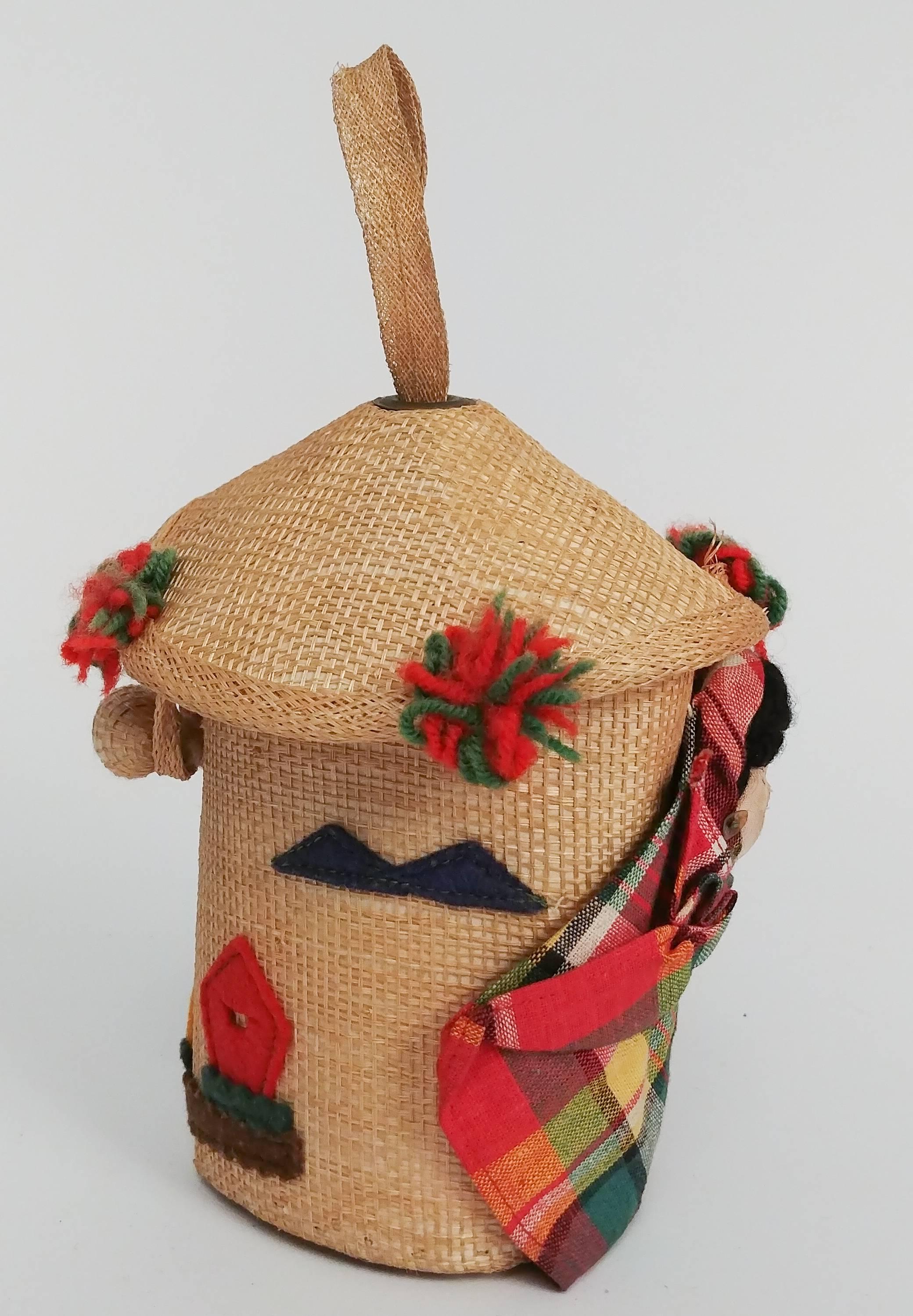 mexikanische Souvenir-Puppentasche aus den 1950er Jahren. Bezaubernde Mini-Tasche aus gewebtem Stroh mit skurrilen dreidimensionalen Details, darunter Pompons aus Garn, Filzlandschaften, Samen und eine eingewickelte Babypuppe. Lässt sich oben mit