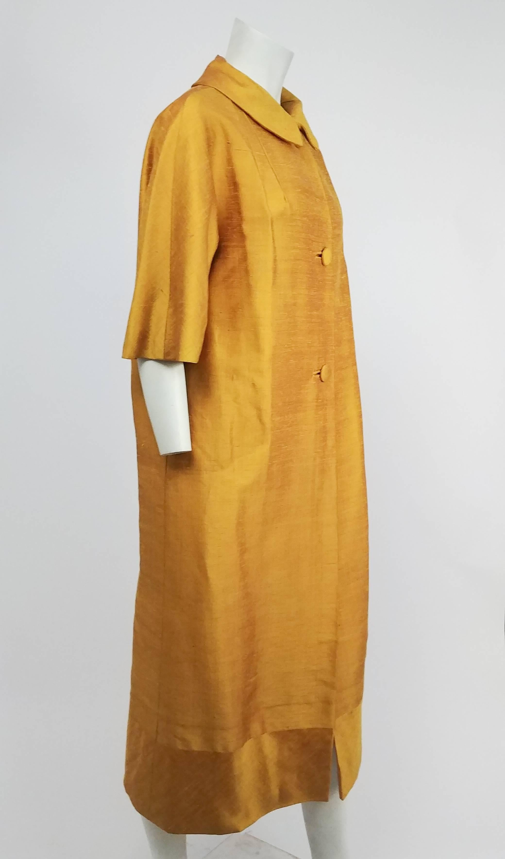 1960s Saffron Yellow Silk Shantung Opera Coat. Buttons up front. Glove length sleeves. Contrast band at bottom with fabric sewn on the bias, creating juxtaposition when light hits the textured fabric.  
