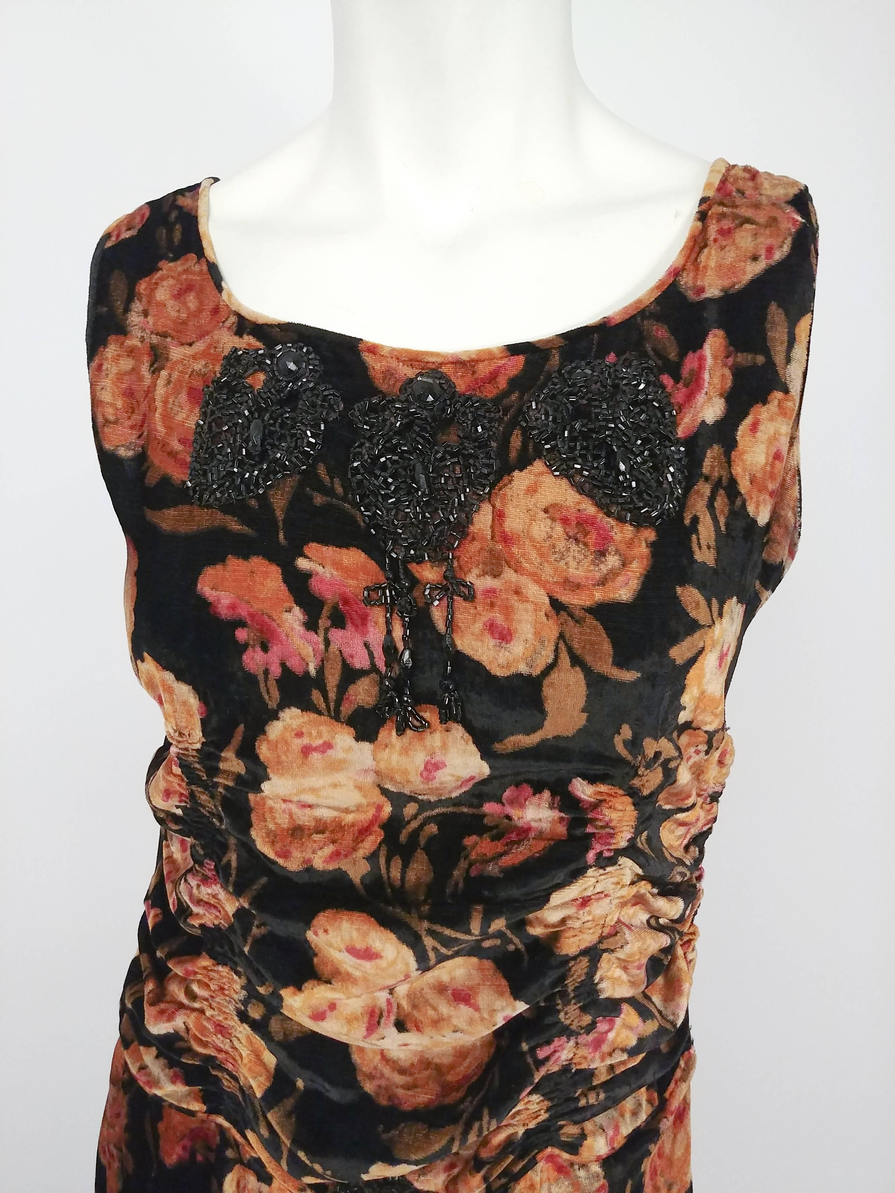 1920s Floral Velvet Dress w/ Black Beaded Applique. Black mesh draped high-low hem. Ruching detail at princess seams. Beaded applique at neckline and waistline. Side snap closure. 