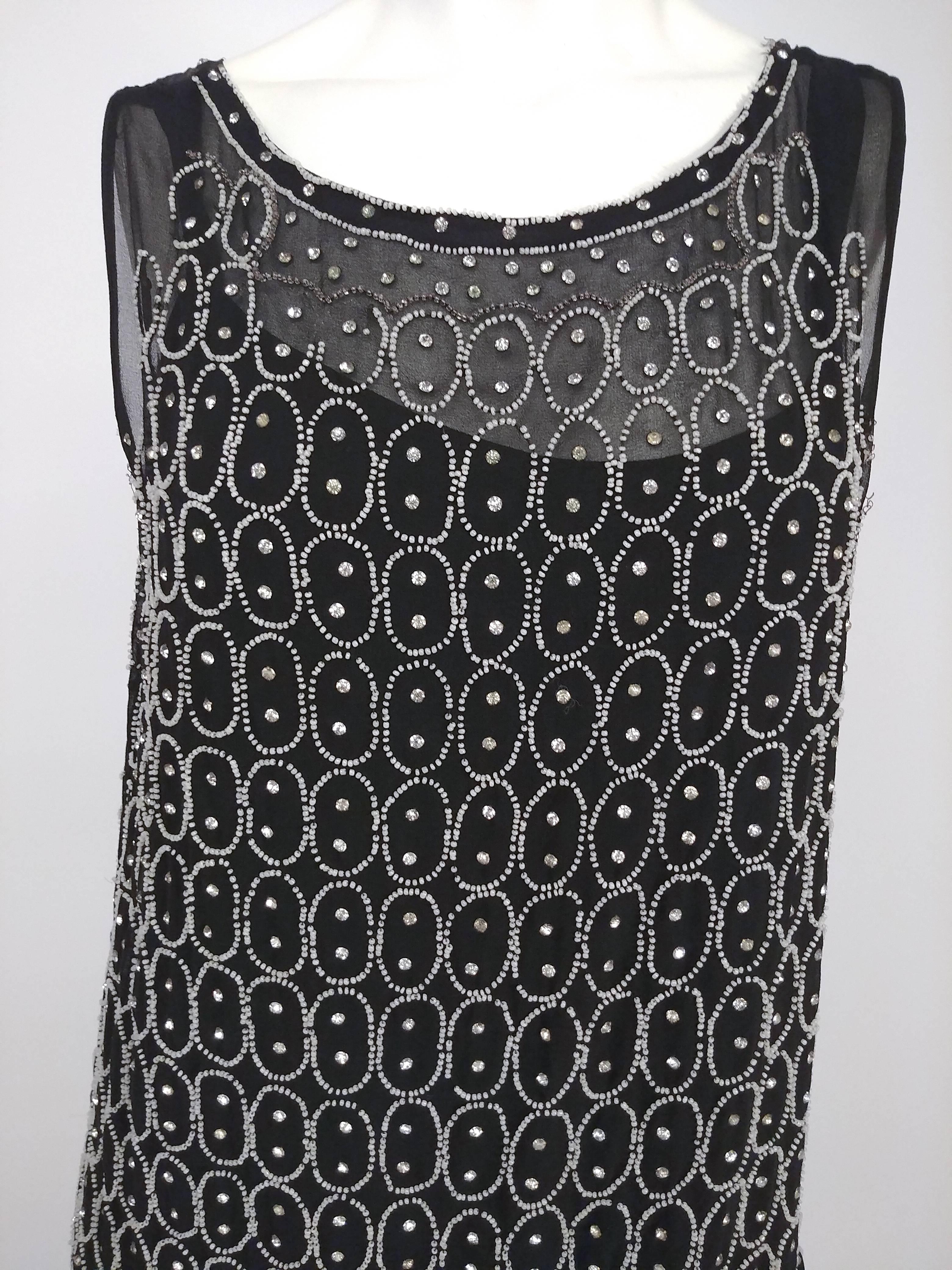 1920s Black and White Beaded Rhinestone Silk Chiffon Dress. Drop waist silhouette with two tier skirt. White beading with additional rhinestones in circular art nouveau design. Slips on over head, no closures. Attached slip. 