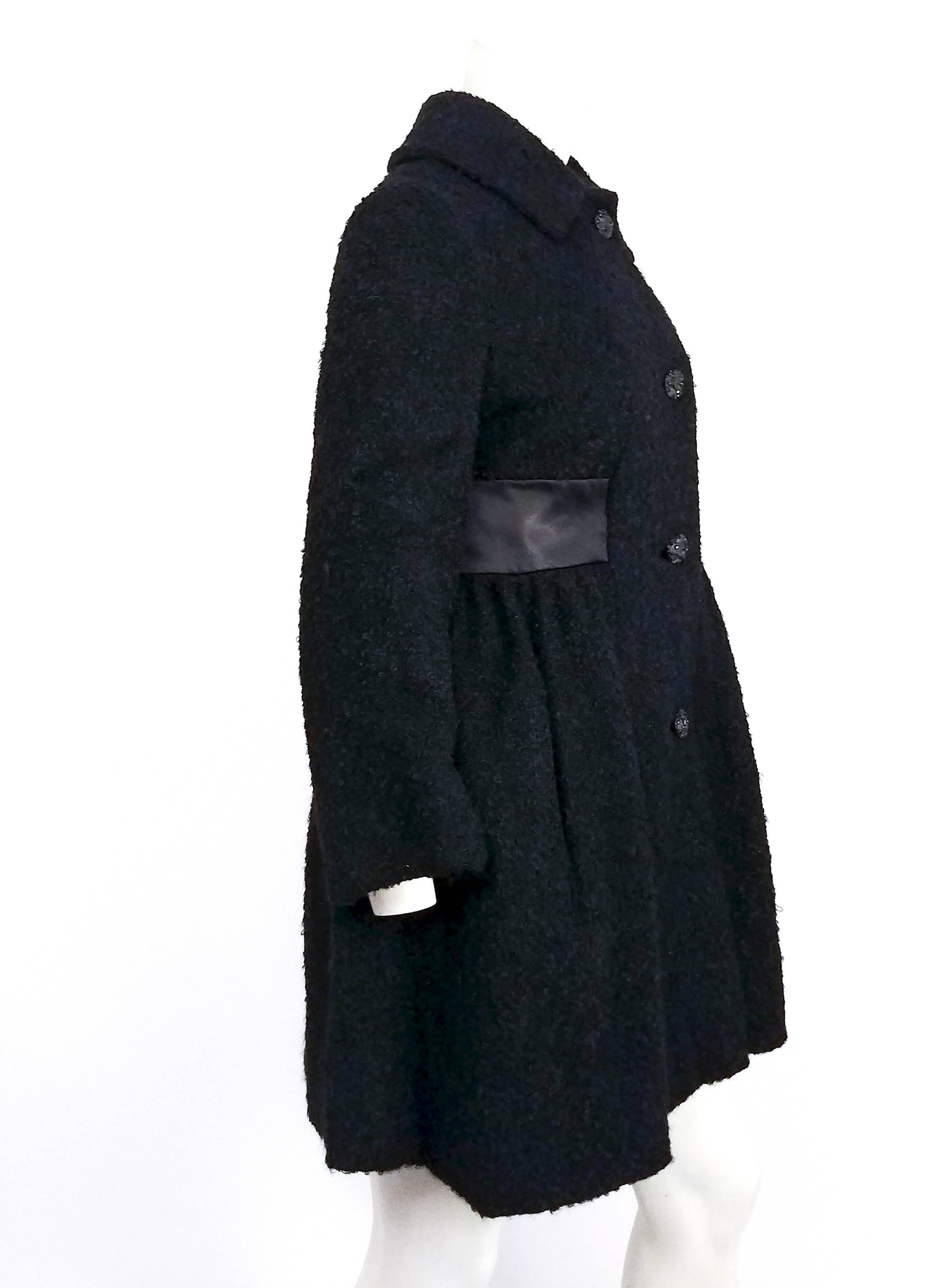 1960s Black Boiled Wool Short Coat. Satin waist detail, gathered skirt of coat flares out in A-line silhouette. Decorative black buttons. 
