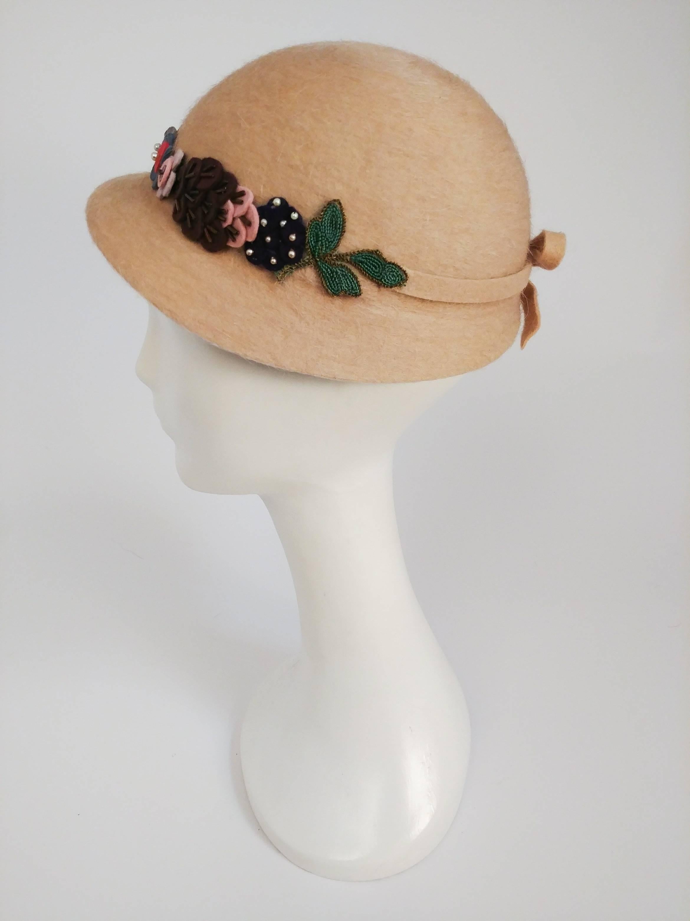 casquette Tan des années 1930 avec fleurs en laine. D'adorables fleurs colorées ornent la bande supérieure de la casquette. Une bande élastique maintient le chapeau en place. 