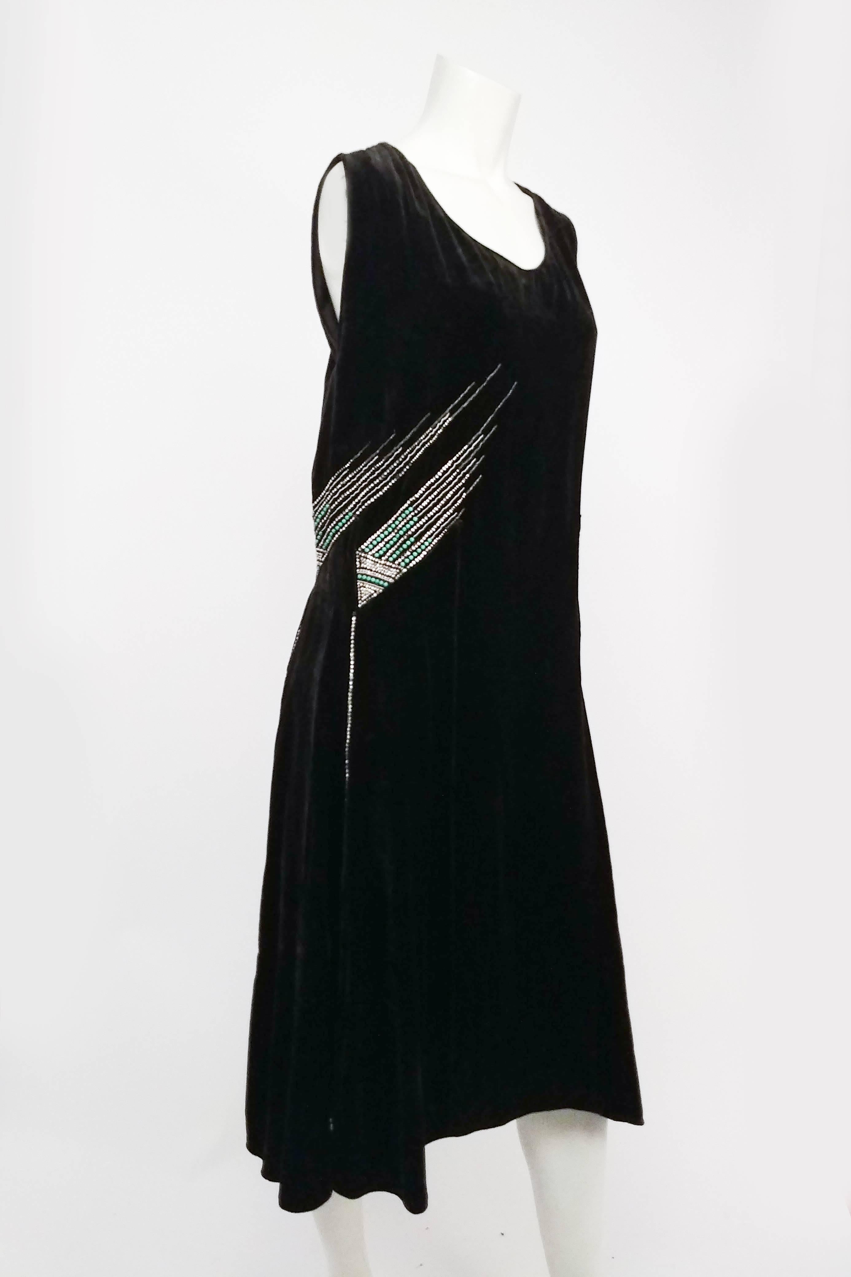 1920s Black Silk Velvet Rhinestone Dress. Rhinestone triangle design at front, with pops of turquoise. V-neck back collar, scalloped back hem with rhinestones leading down to swirled designs. Sewn-in shaped gores. No closures, slips on over head. 