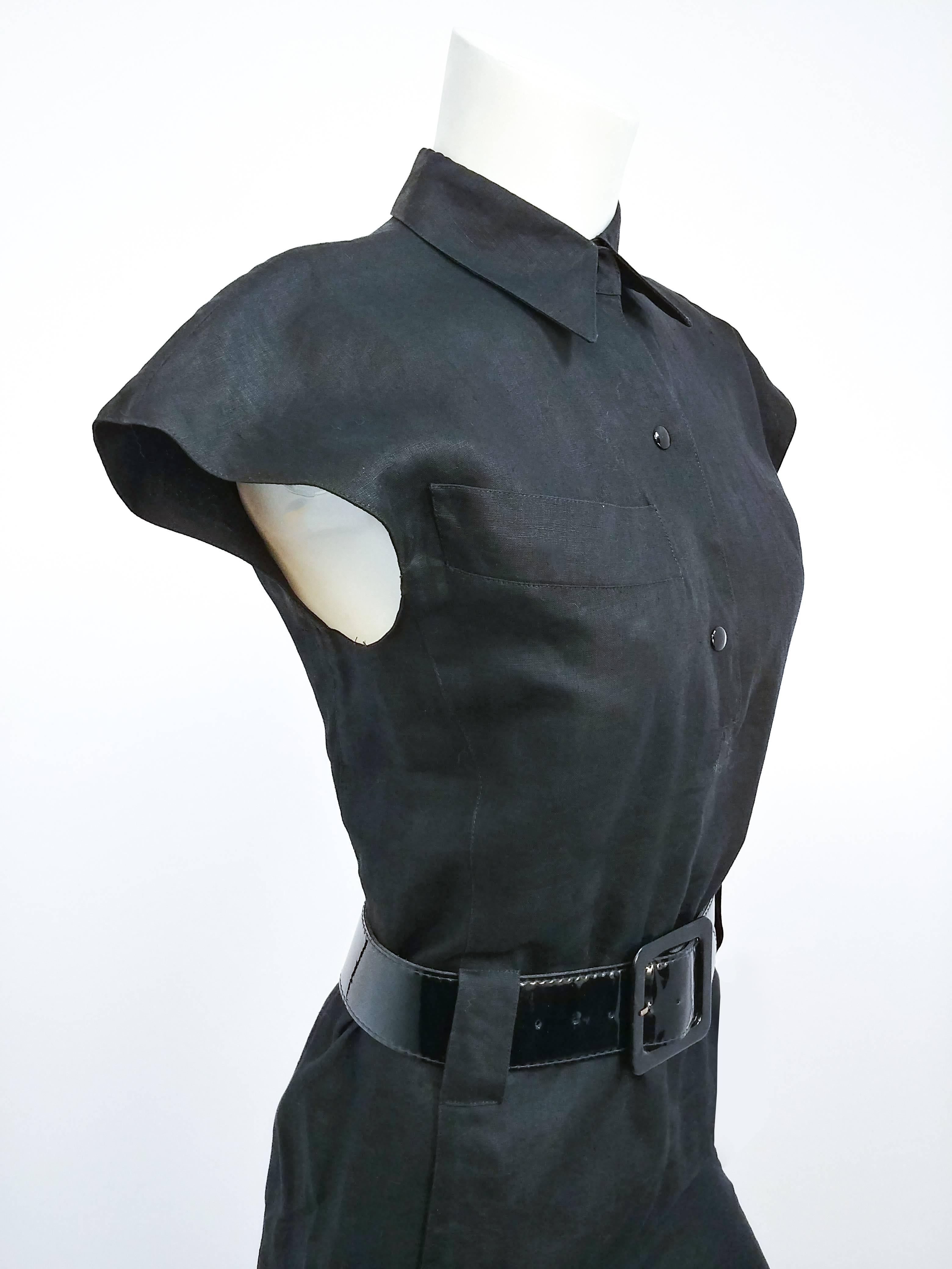 Vestido camisero de lino negro Claude Montana de los años 80. Botones a presión delante, cuello camisero, un bolsillo delantero en el pecho. Cinturón ancho de charol. Dramático pliegue de patada. 