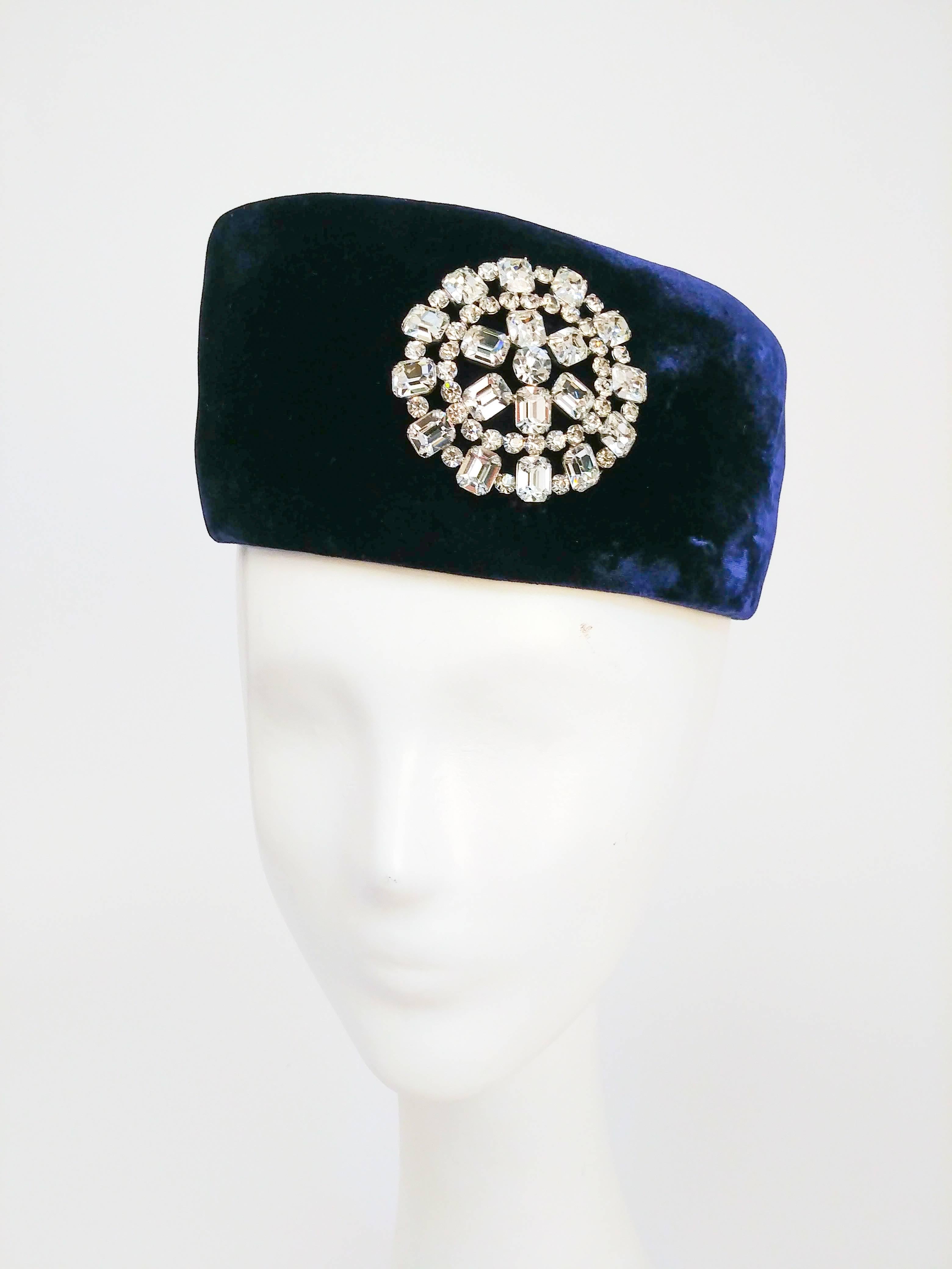 1960s Blue Velvet Hat with Rhinestone Embellishment. Dark blue velvet hat with grosgrain bow, and clear rhinestone and silver-tone embelishment. 21-1/2 inch circumference.