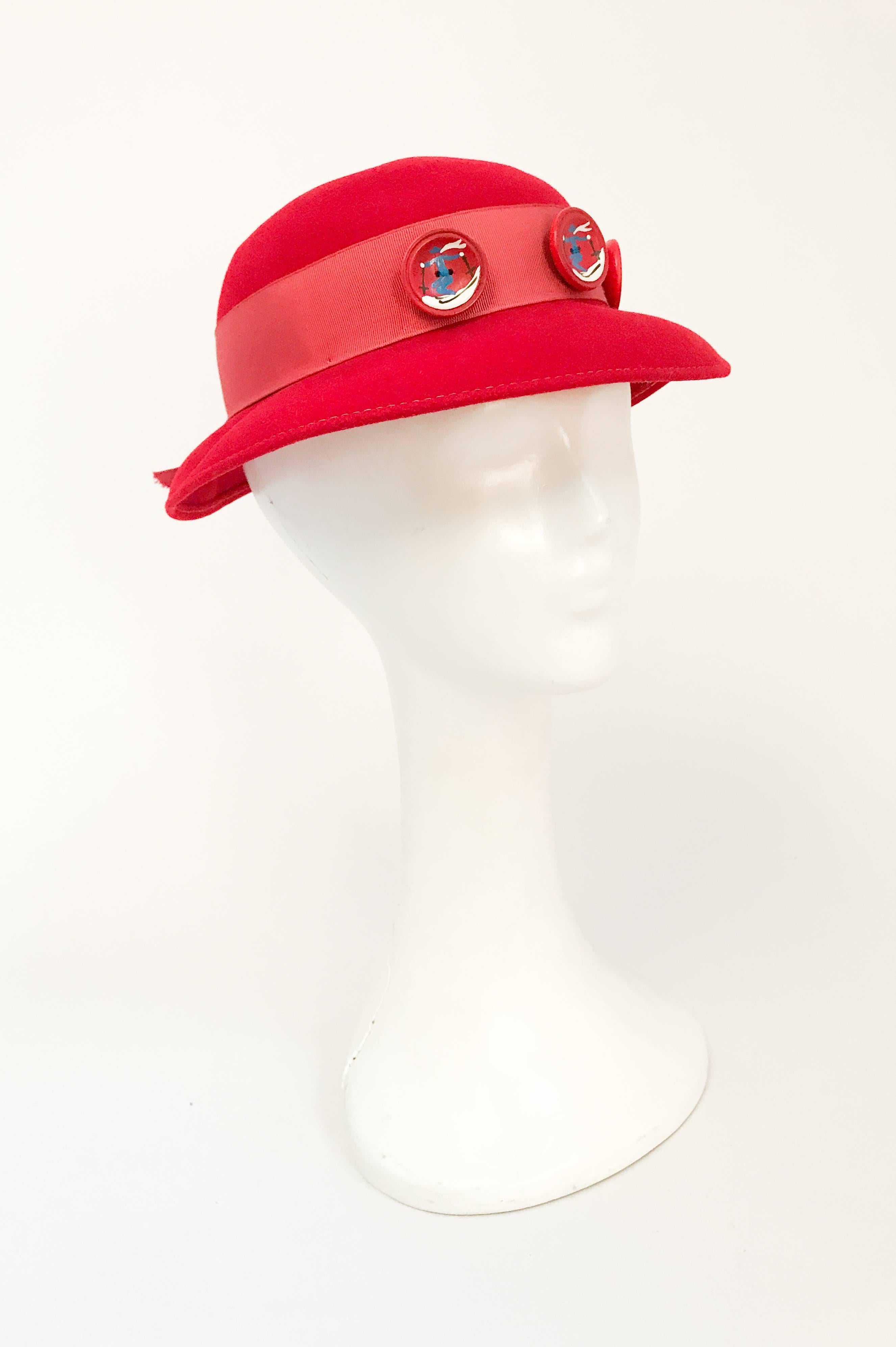 1930s Red Felt hat with Hand Painted Ski Buttons. Red felt hat with wide grosgrain band, back opening and Hand painted ski motif buttons. 