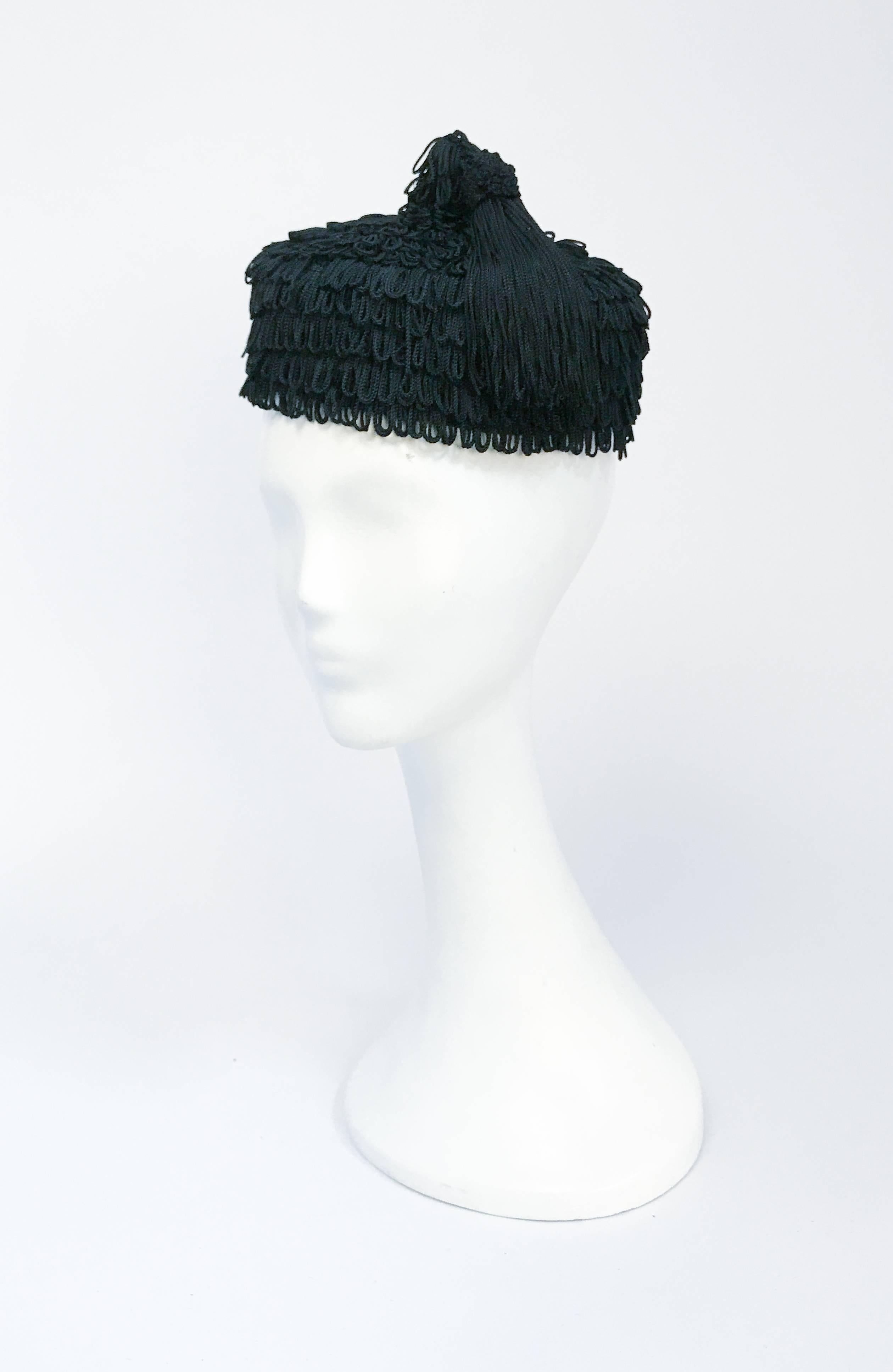 Chapeau à franges noir des années 1940 avec pompon assorti. Chapeau à franges en rayonne noire avec pompon assorti. Élastique pour fixer le chapeau sur la tête.