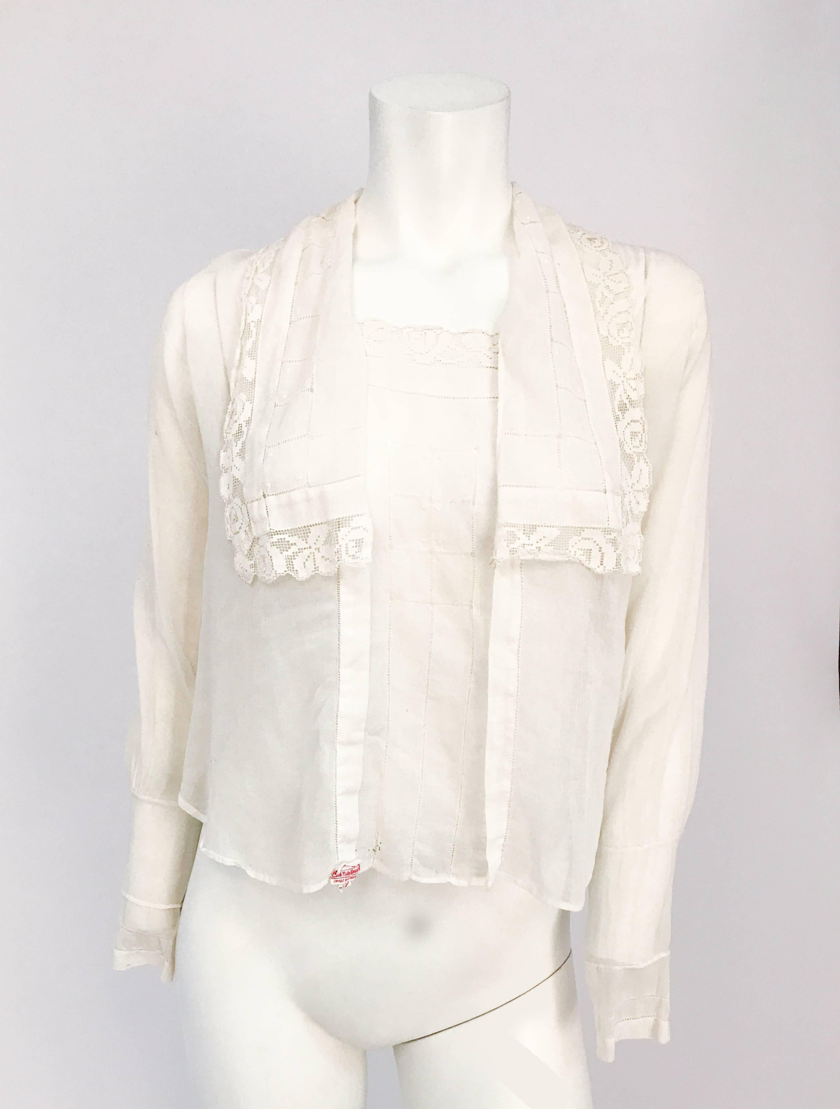 Weiße Bluse aus den späten 1910er Jahren mit Spitzen- und Zugarbeiten. Handgefertigte Bluse mit Durchzug, französischem Knoten und passendem Spitzenbesatz. Übergroßer Kragen mit Muschelknöpfen und Haken- und Ösenverschlüssen.