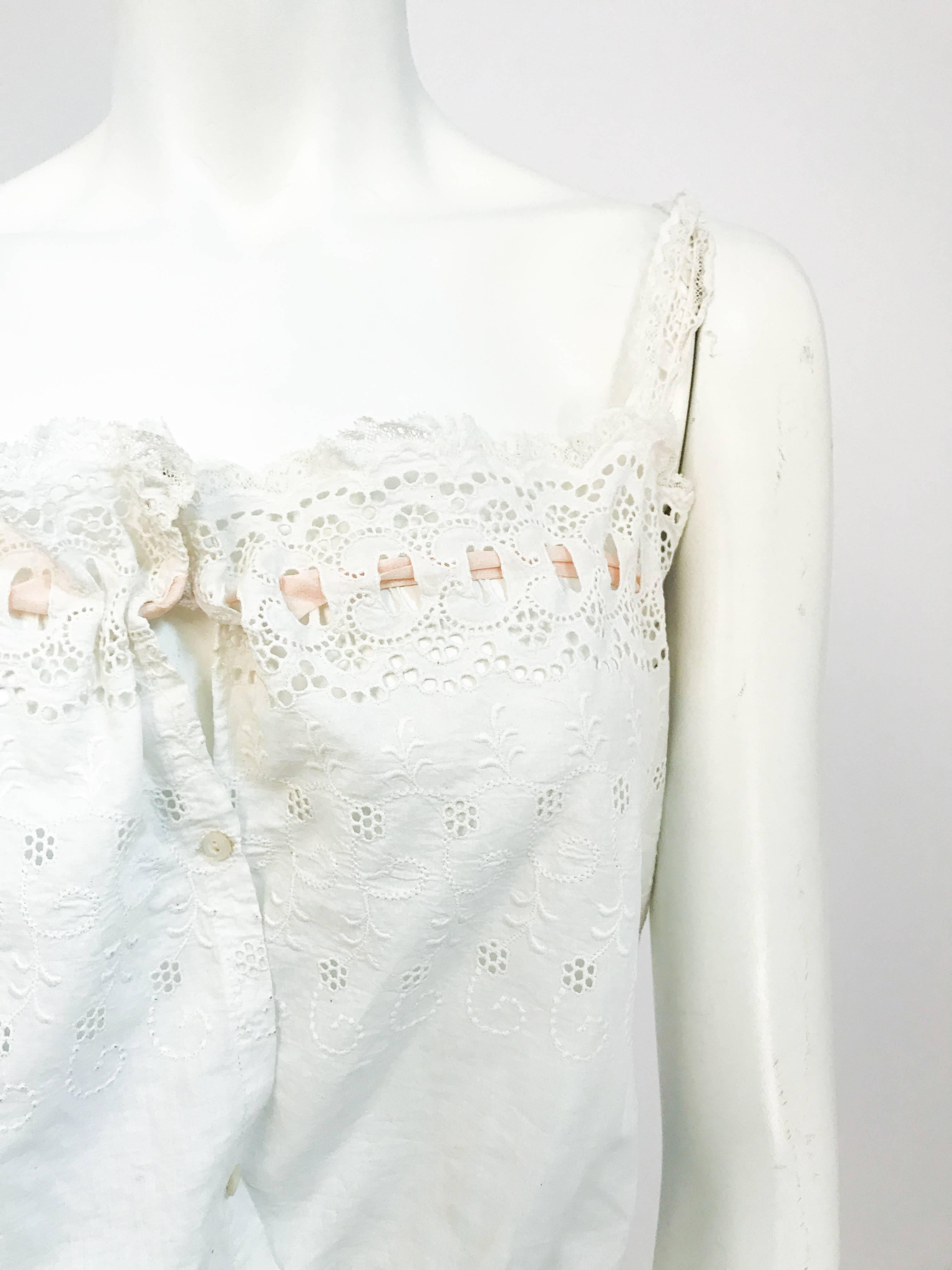Edwardian white cotton eyelet corset top with with cut work along neckline and shoulder straps. Peach Ribbon strung though cutwork. Seashell button front closure