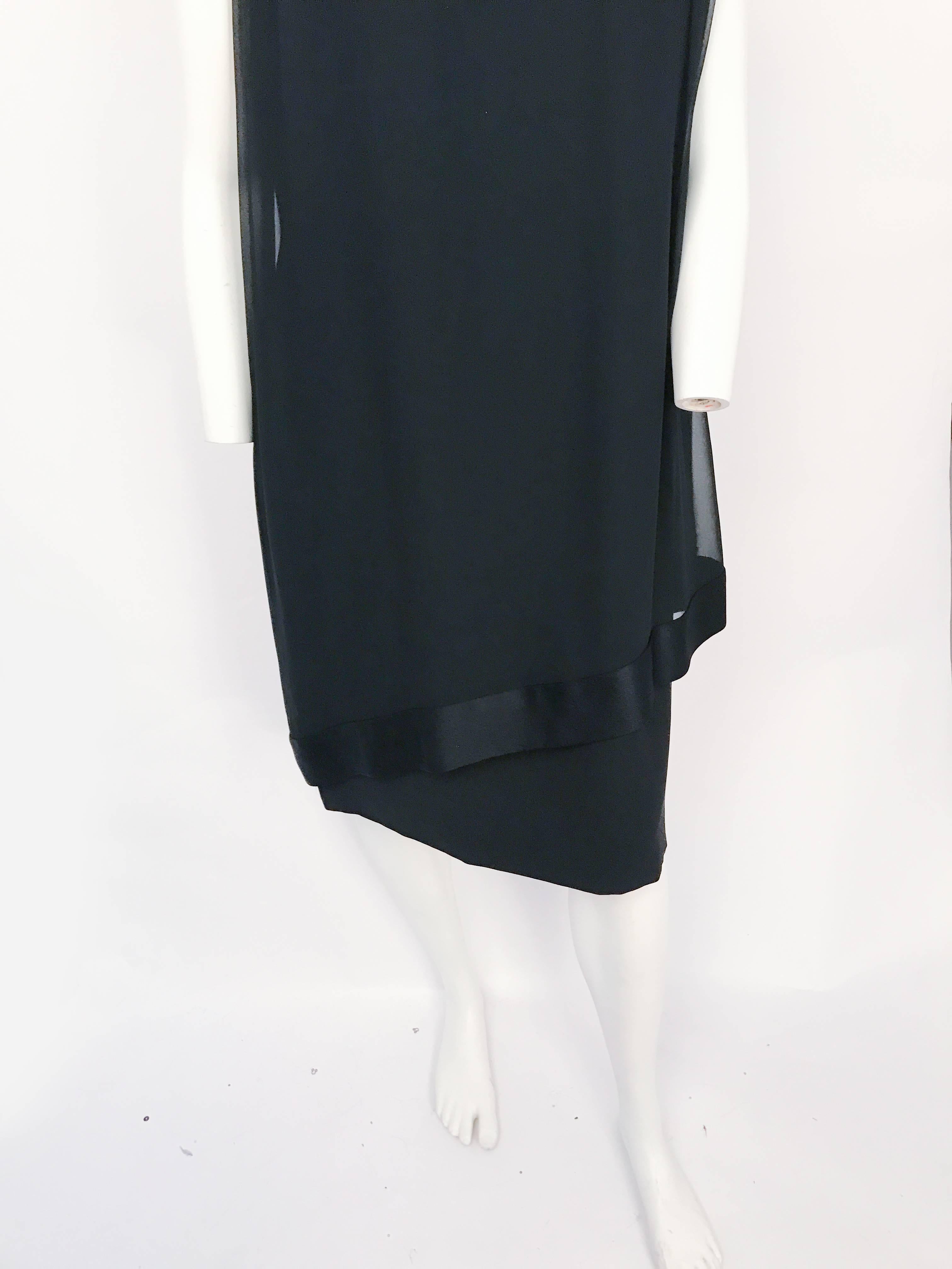 1960s Black Silk Crepe Sheath Dress with Chiffon and Satin Drape. Black silk crepe sheath dress with silk chiffon and satin asymmetrical drape in the front and an oversized bow and gathering along the back. It has the original metal zipper and hood