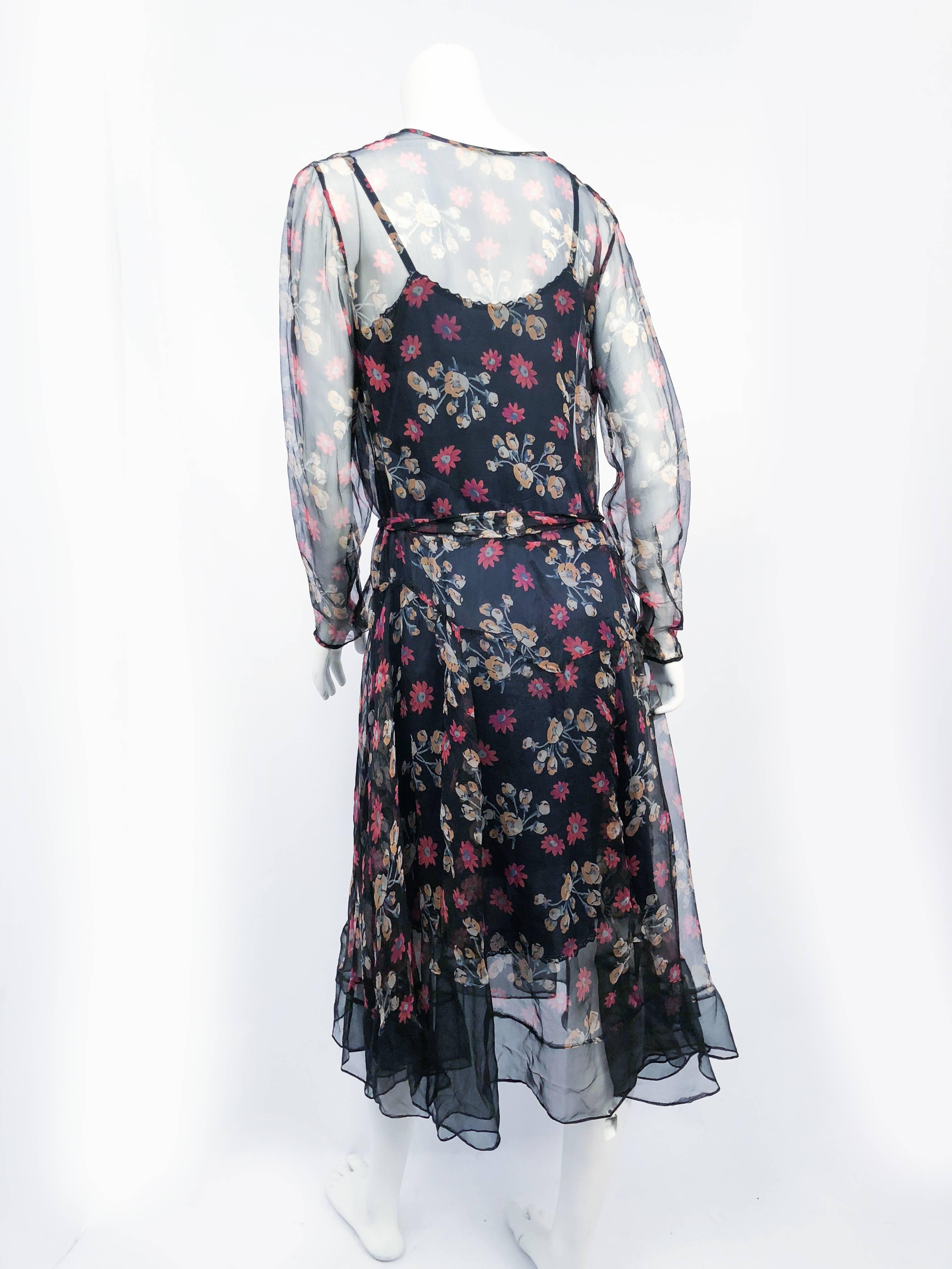 1920s Sheer Floral Printed Silk Chiffon Dress. Sheer floral printed silk chiffon dress with black background color. Full length tapered sleeves and drop-waist. Matching head sash. Hemmed with sheer black ruffling and goring in the skirt for extra