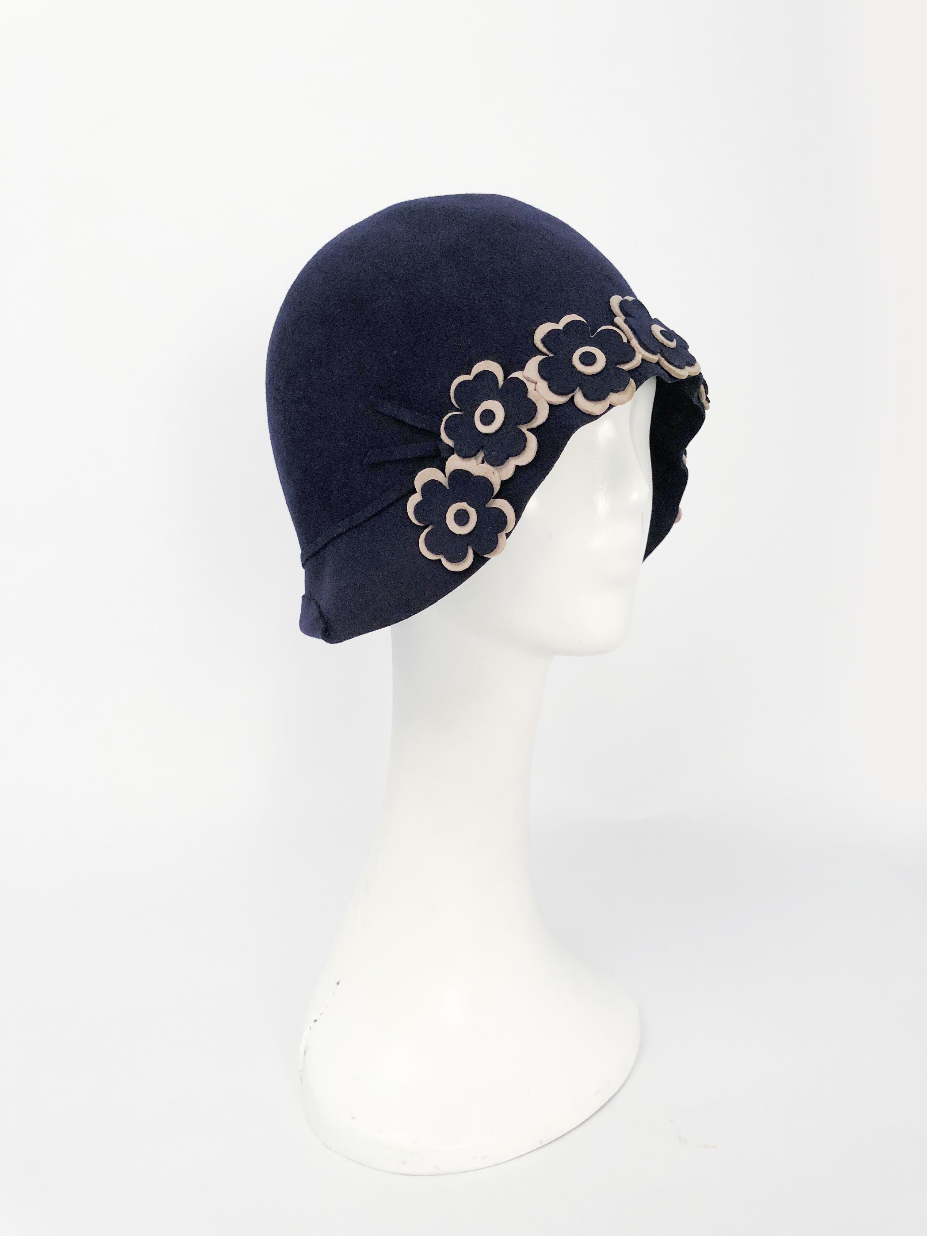 1920s Navy Beaver Felt Cloche with Hand cut Flower Accents. Navy beaver fur felt cloche with hand-cut navy and beige flowers along the brim of the hat. Also has a thin matching hat band that goes all the way around the hat. 
