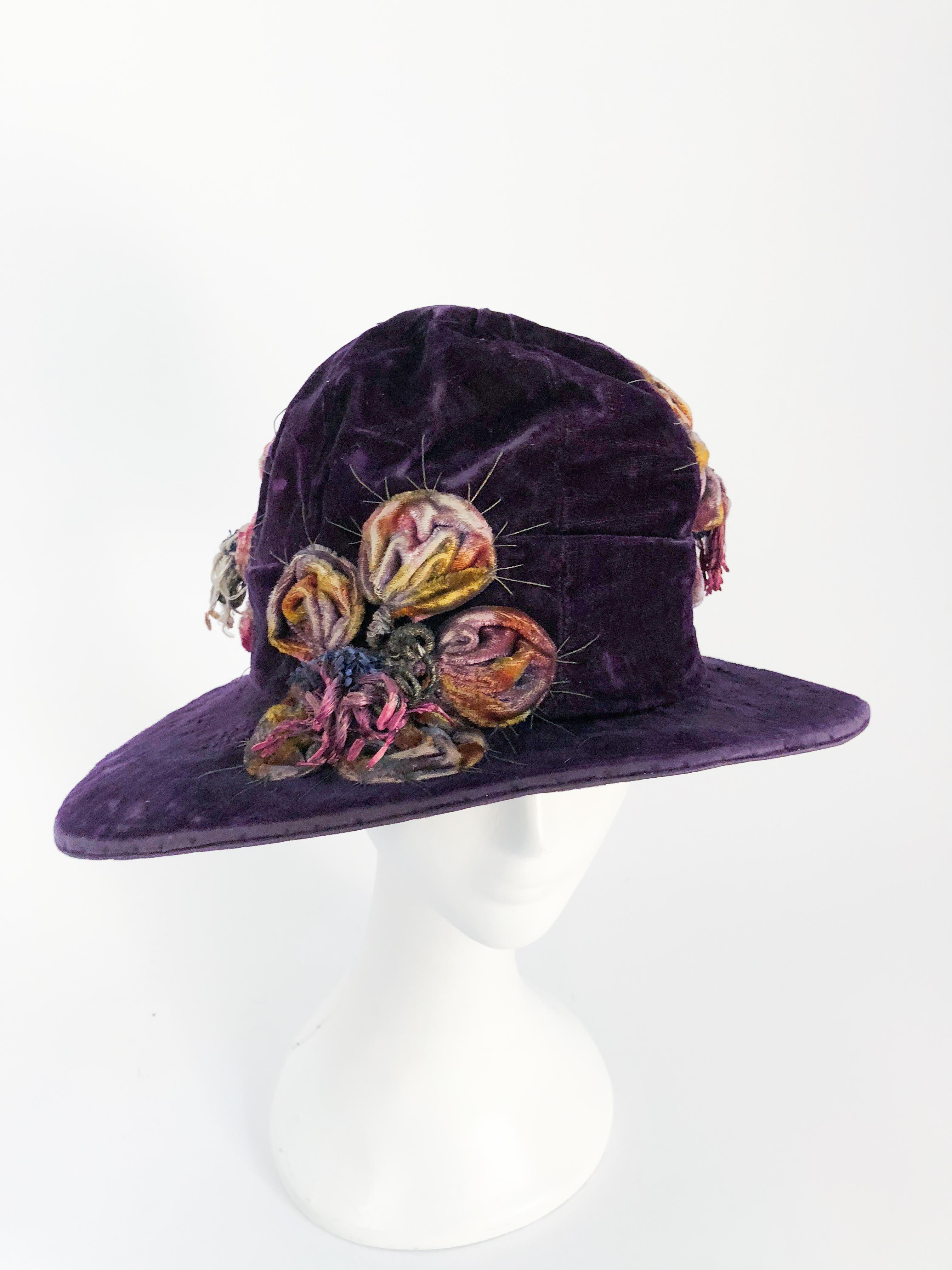 1920s Purple Velvet Cloche With Flower Accent Pieces. Very early 1920s purple velvet cloche wiht stuffed 3D multi colored flowers with brass threaded details that come out of the three flowers