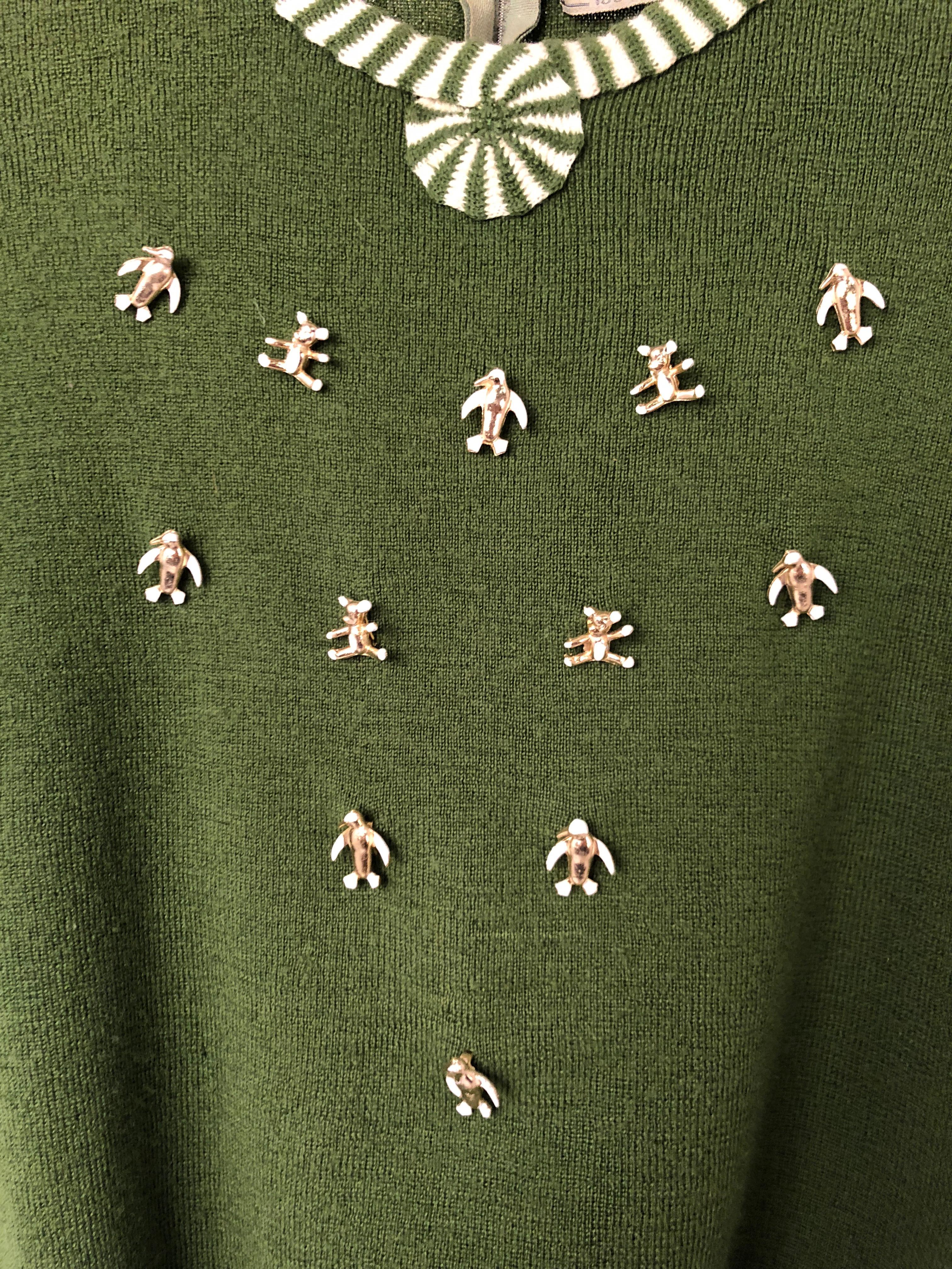 Avocado green short sleeved sweater with matching green and cream applied trim on sleeves and neckline. Customized with metal brass penguin and bear studs. Zipper along the back of the neck. Due to this garment being knit, it does have stretch to it.