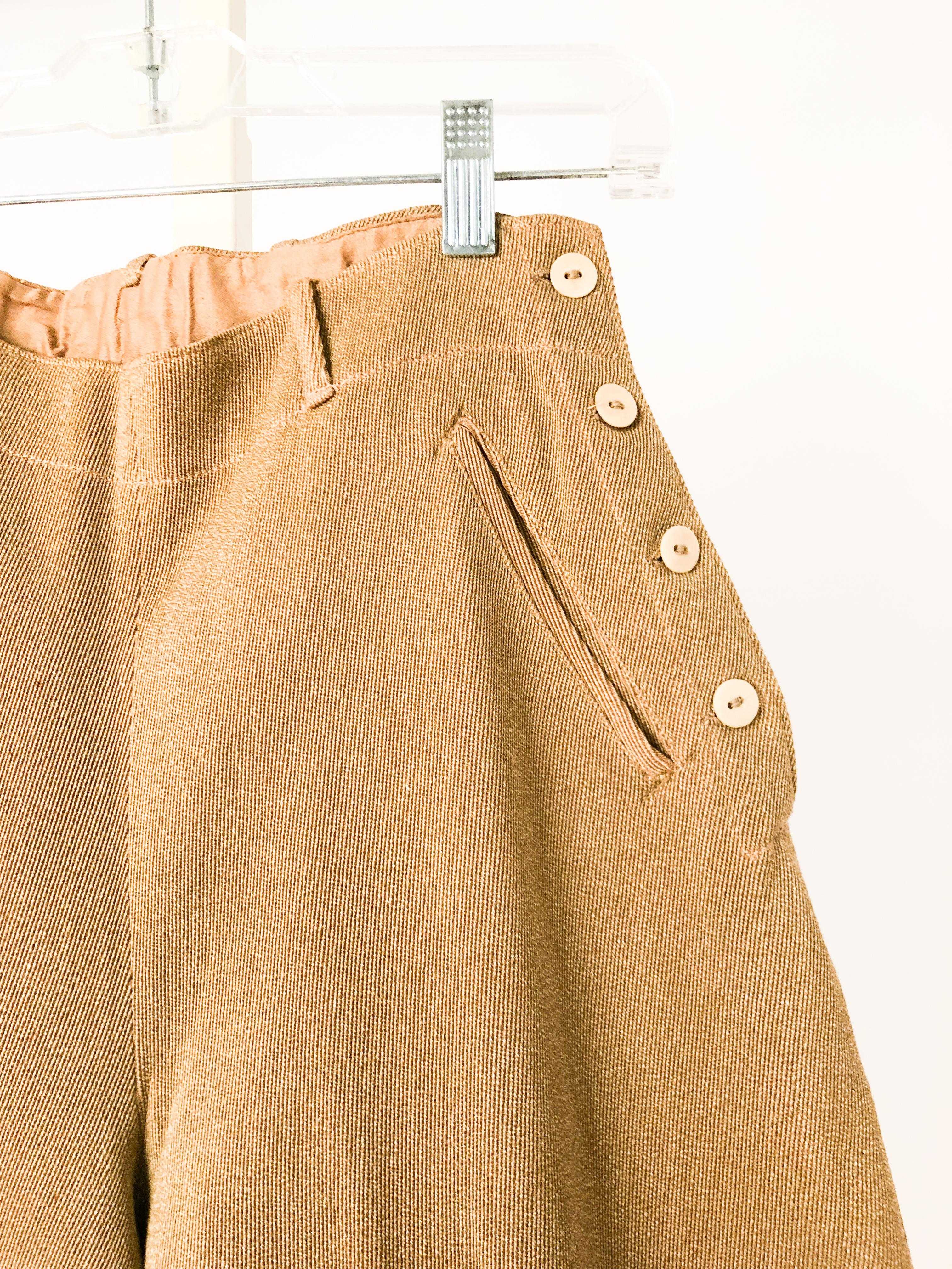 Tan with flecked color texture jodhpurs made of a heavy twill and applied suede grip pads, finished cuffs, sturup buttons, and celluloid buttons on the closure.