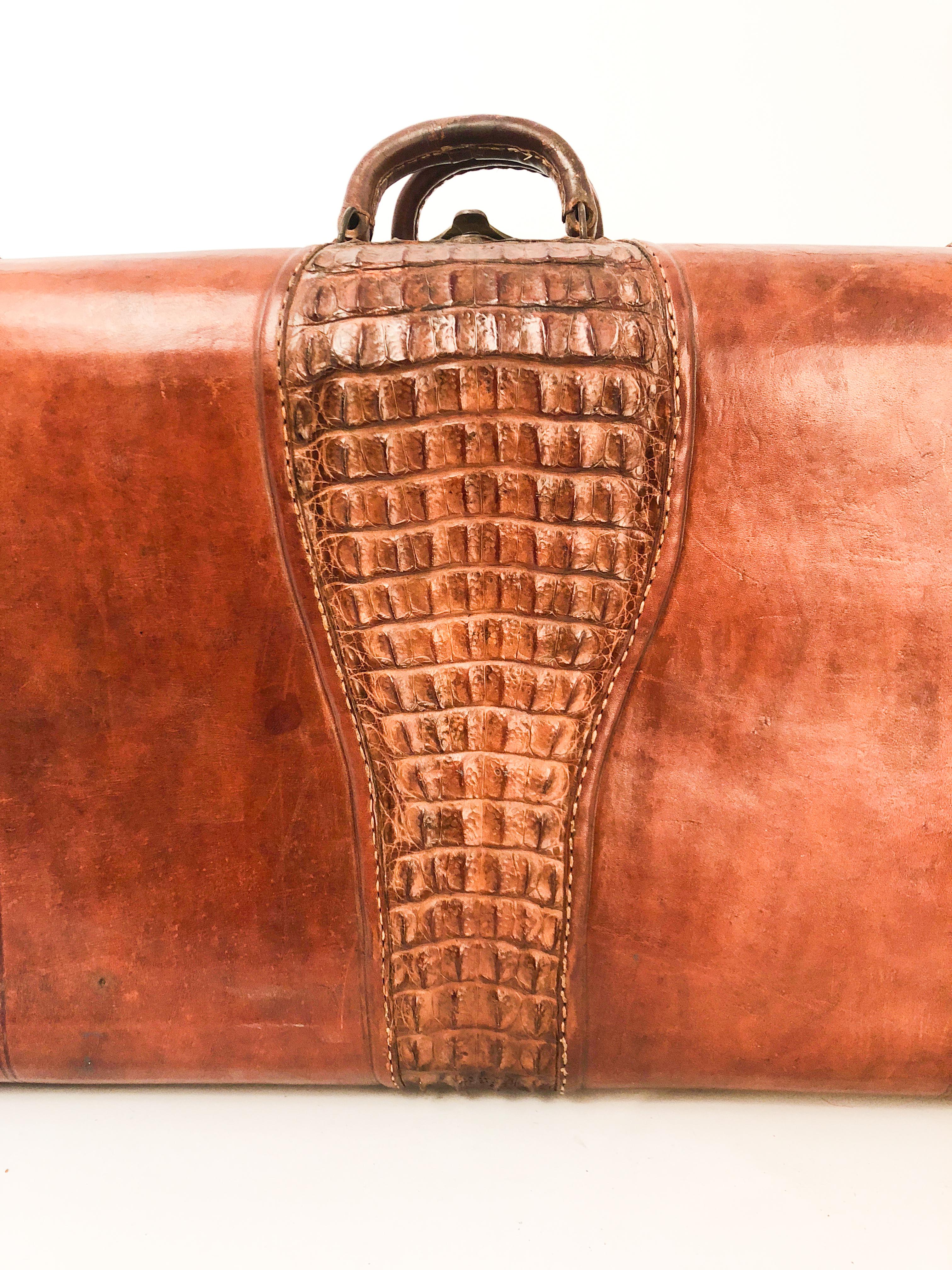 Valise en cuir fabriquée sur mesure avec un panneau central en caïman appliqué. Doublure en toile avec compartiment central. 