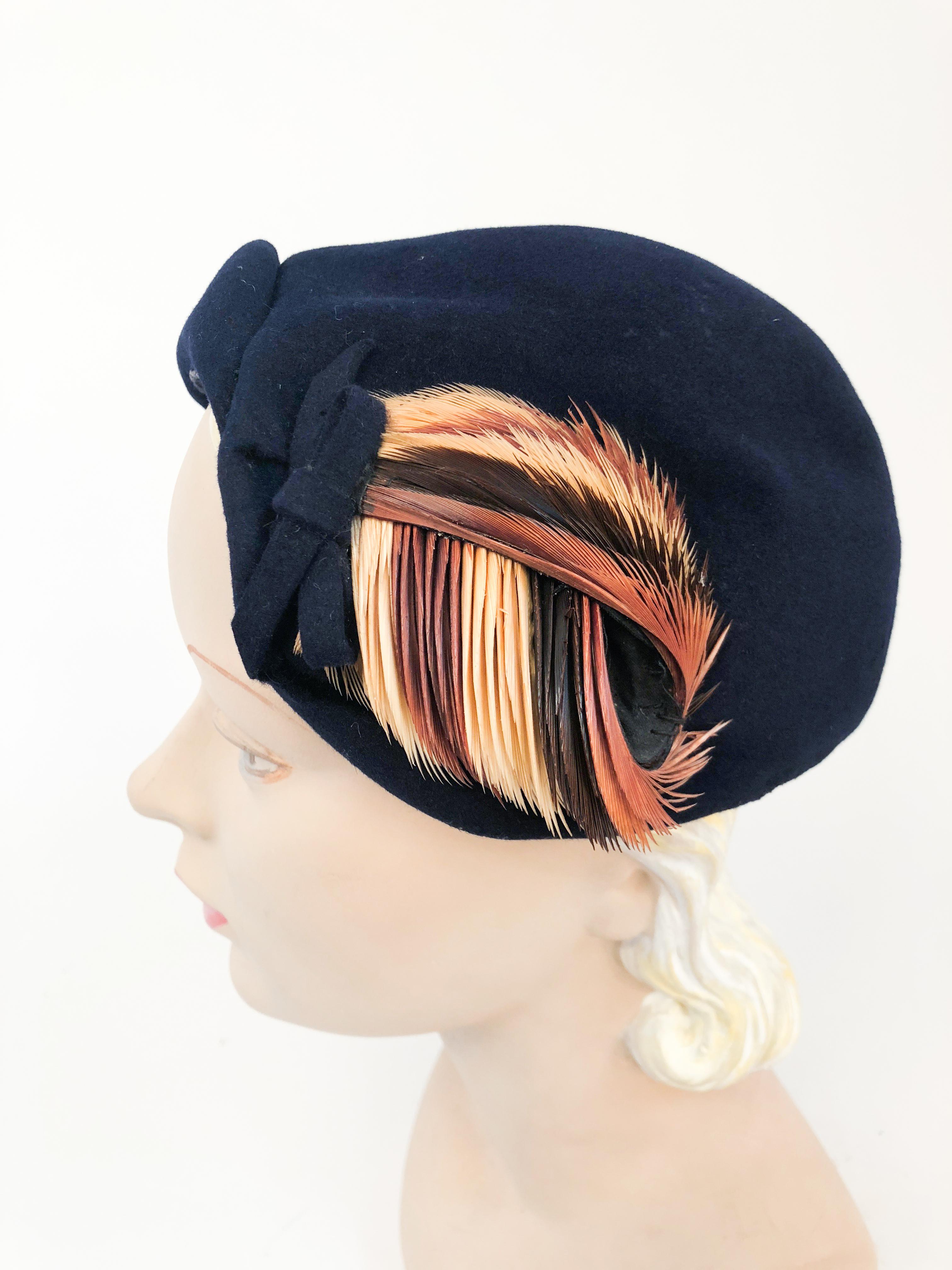 1950s Navy Felt hat with Decorative Feathers that are multi-colored shades of brown. This hat is asymmetrically shaped and has a decorative bow