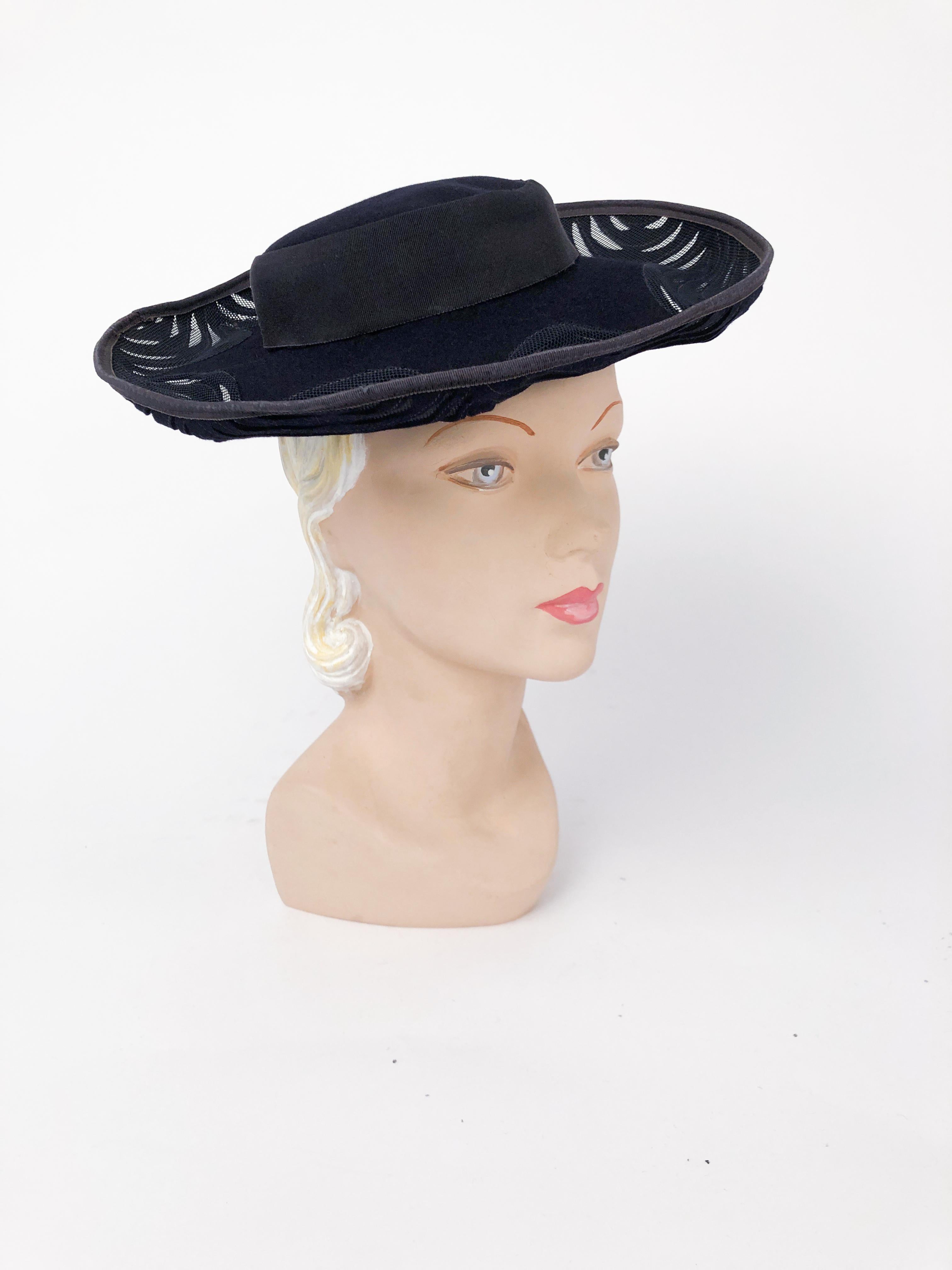 1940s Navy Felt Hat with Hand Cut Pattern and Netting. Navy blue fur felt hand cut pattern with shallow crown, wide brim, grosgrain trim and matching net.