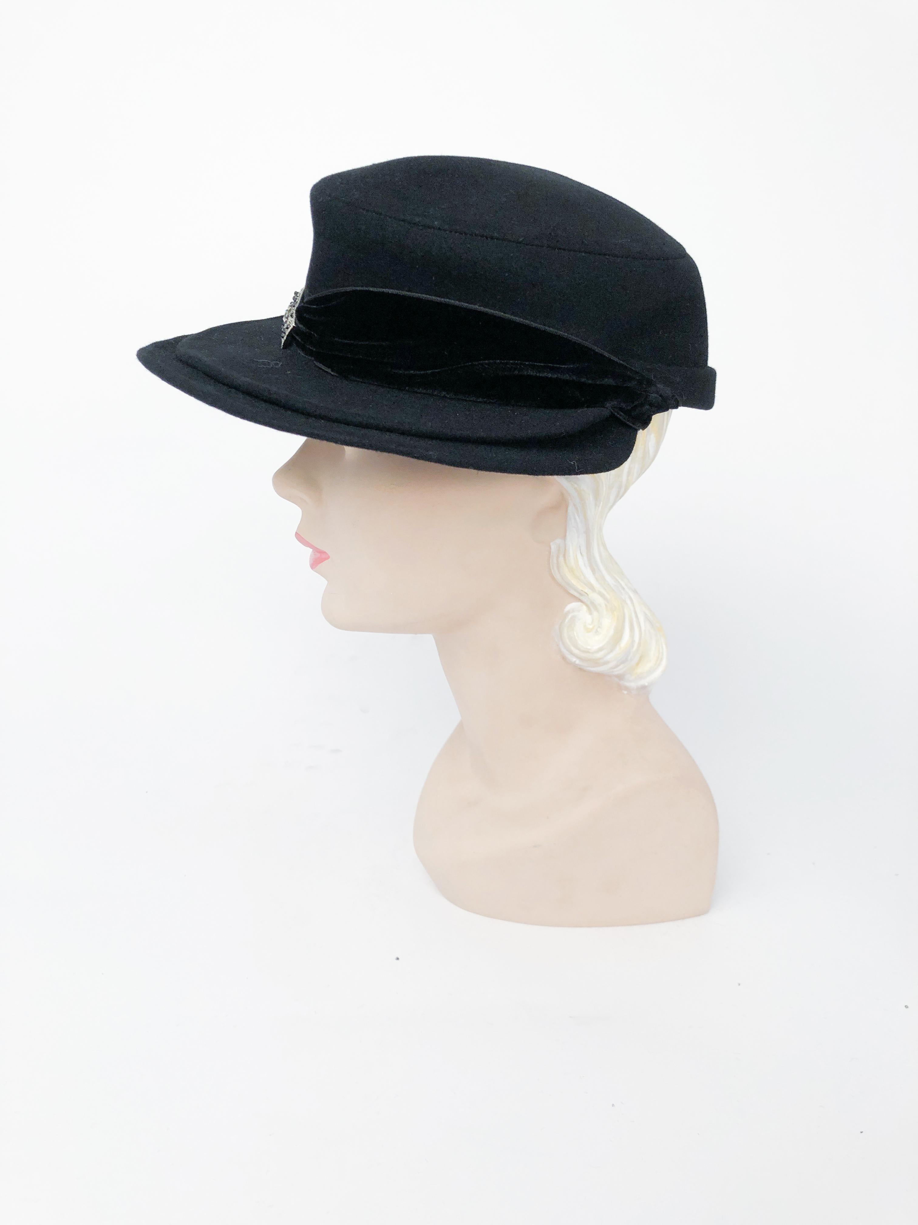 Schwarzer Hut aus Biberpelz mit doppeltem Schnabel, Samtband und Juwelenakzent.