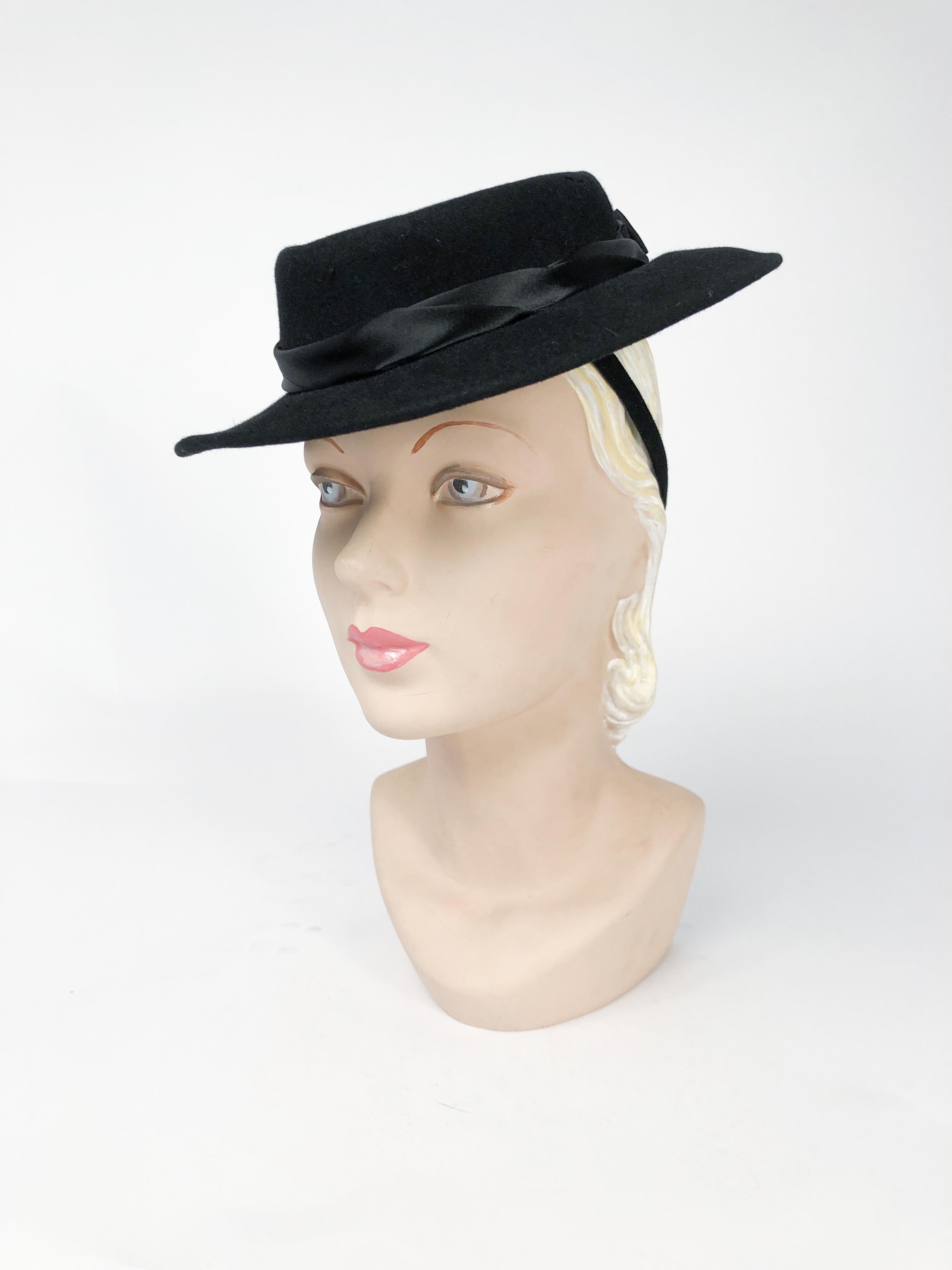 Black cashmere felt hat with hand-rolled silk satin band, layered bow, and rhinestone accent (black and clear rhinestones). Felt hat band with elastic attachment to further secure the hat to the head. 