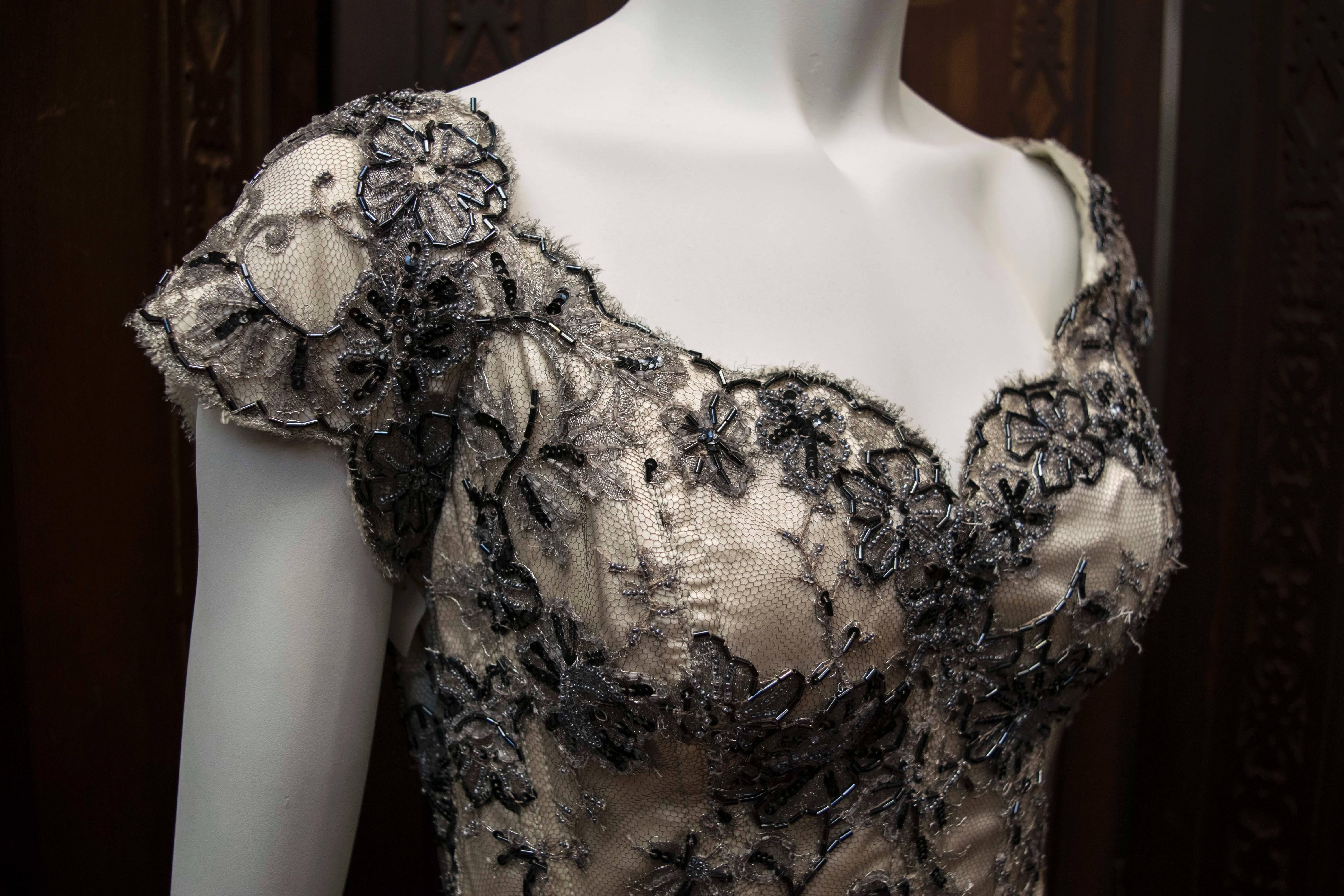 Vicky Tiel Corseted Evening Gown.
A stunning corseted evening gown designed by Vicky Tiel. The piece boasts a silver lace train and detailing. This couture gown looks absolutely gorgeous on! 