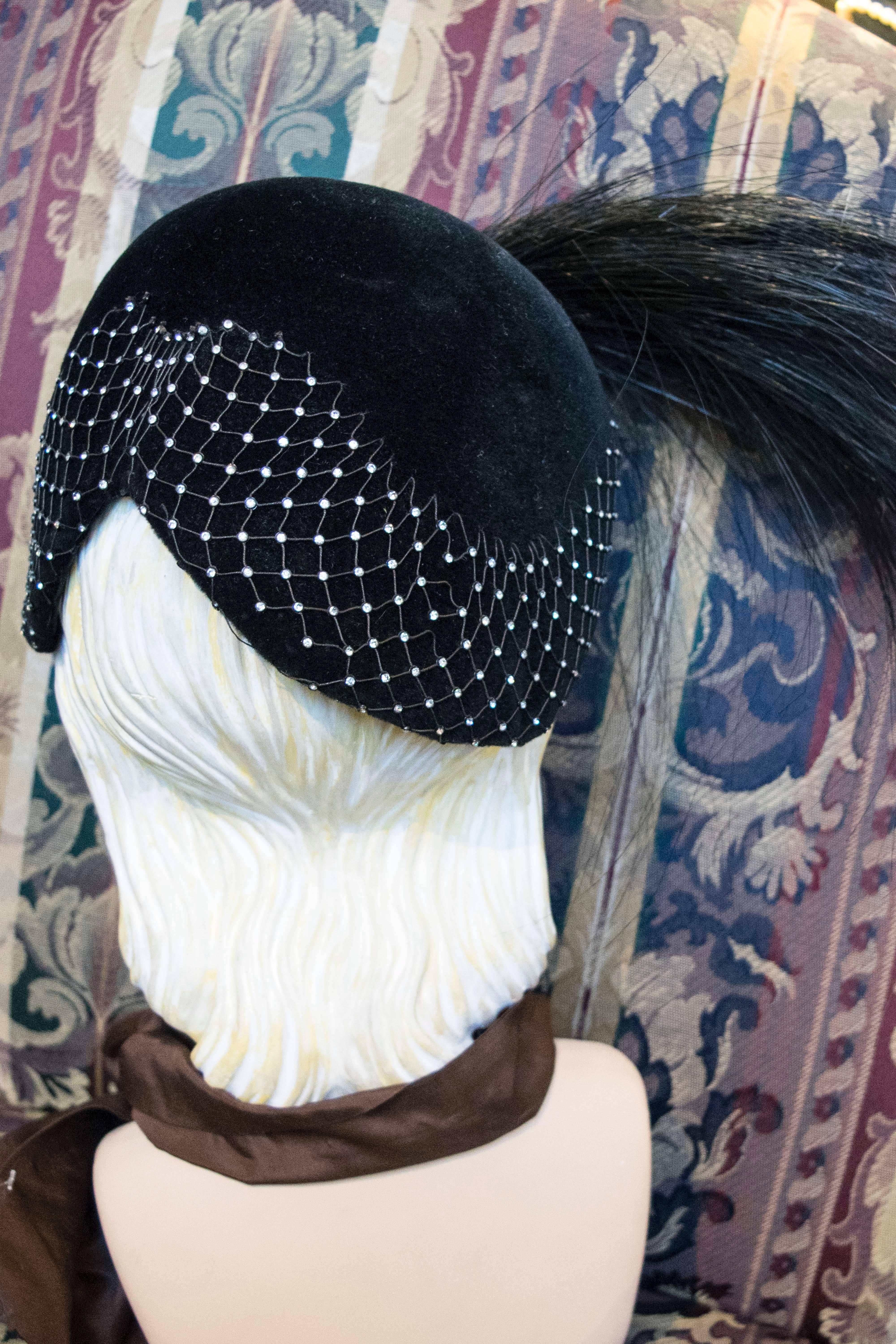 1950s Black Velvet Cocktail Hat
A astonishing piece of wearable sculpture, this piece features a copper basket weave net, studded with rhinestones, and if that was not enough it also has a magnificent horse hair plume! This piece would be right at