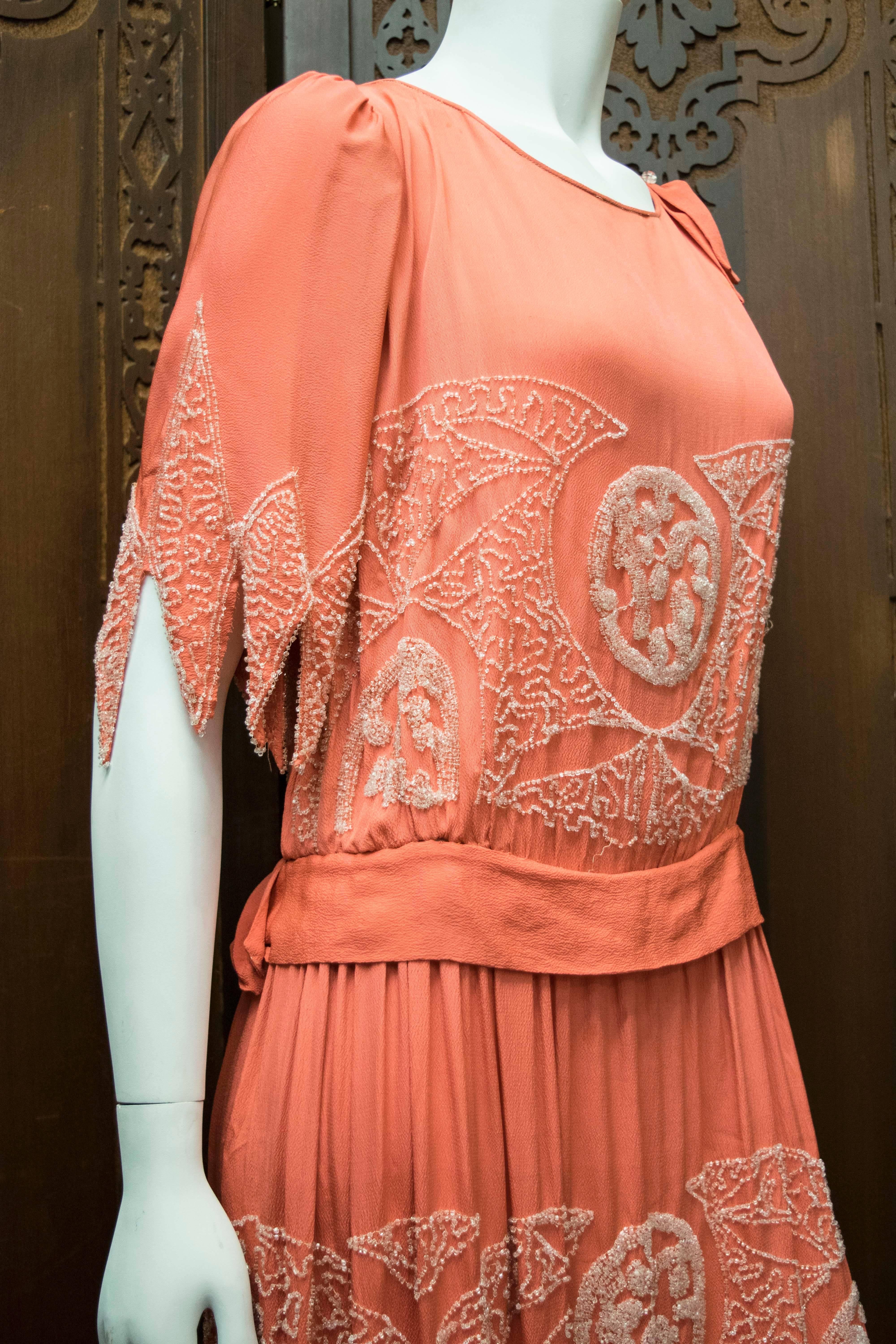 1920s Pink Beaded Flapper Dress.
A Beautiful Salmon pink mid-late 1920s flapper dress. The entire piece has been hand beaded, and the stunning handkerchief sleeves and hem have a gorgeous weight and movement to them as a result. The piece has its