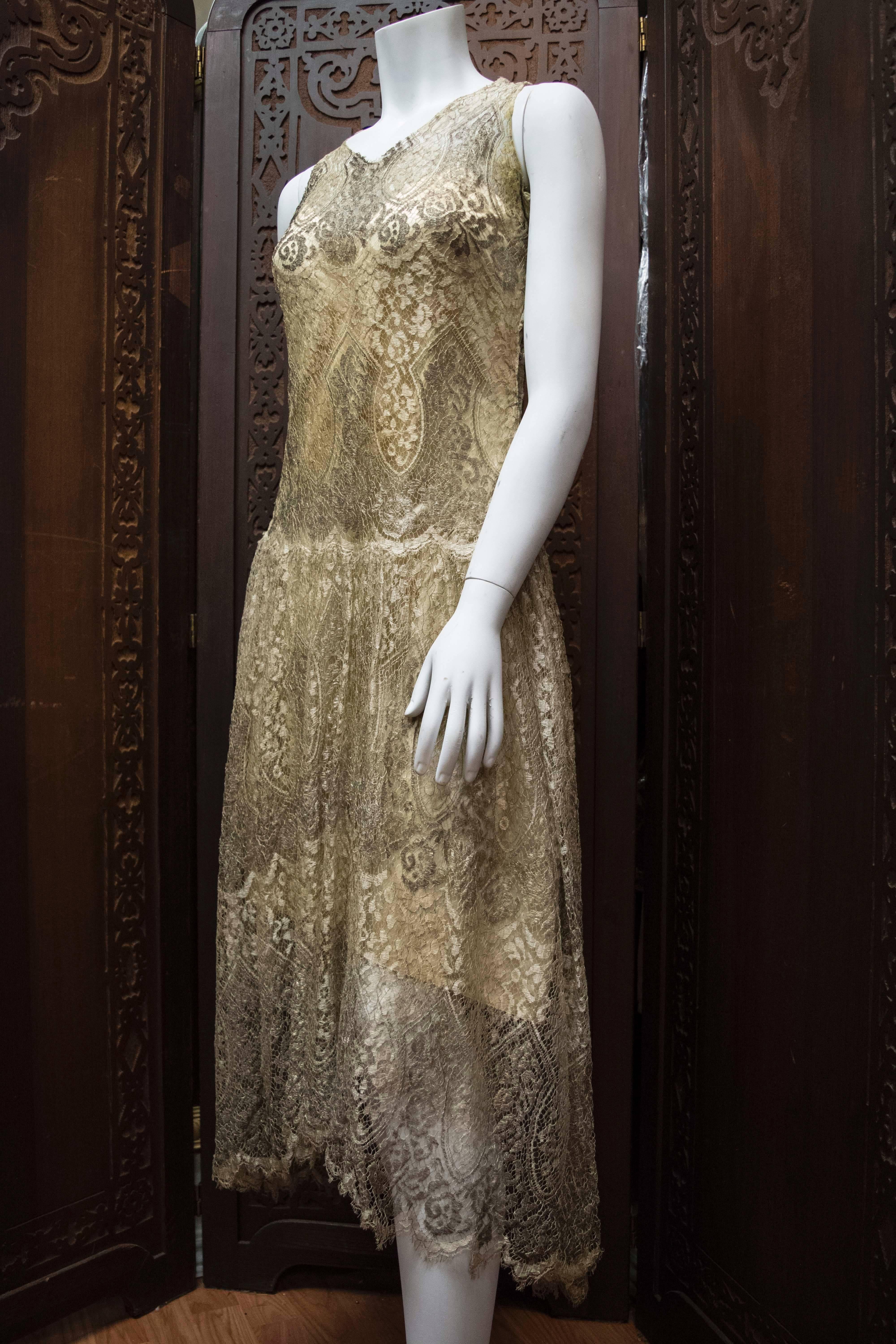 1920s Silver Lamé Lace Dress

An absolutely stunningly intricate late 1920s lace dress. This piece is incredibly rare, constructed from silver lamé lace threads and original cream-beige silk interior scaffolding. The piece is gusseted past the hips