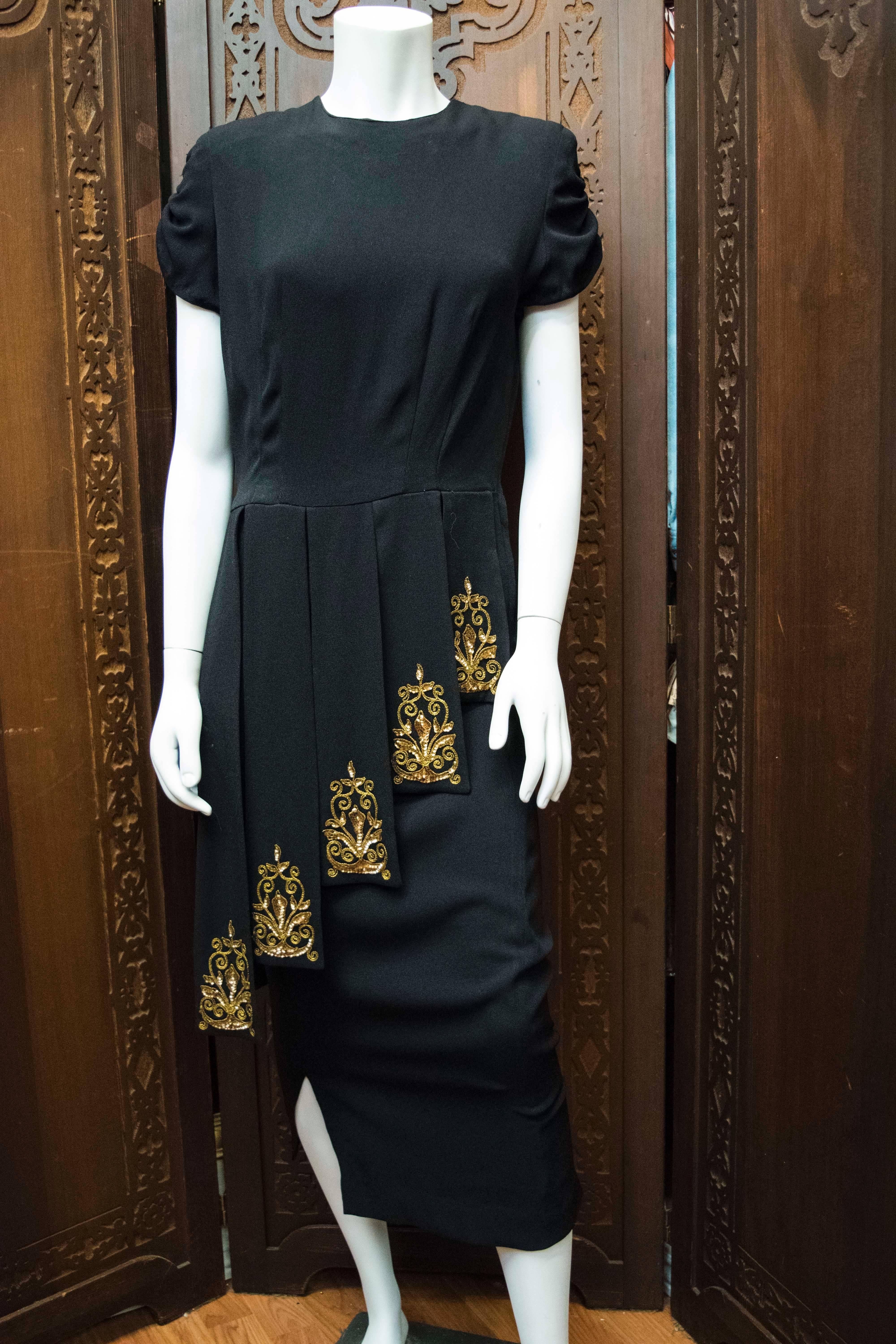 1940s Film Noir Cocktail Dress. Designed by Eisenberg and Sons who are also famous fo their jewelry.

Stunning 1940s dress with graduated gladiator panelling with gold lamé thread embroidery. 

B 36
W 30
H 38
L 50