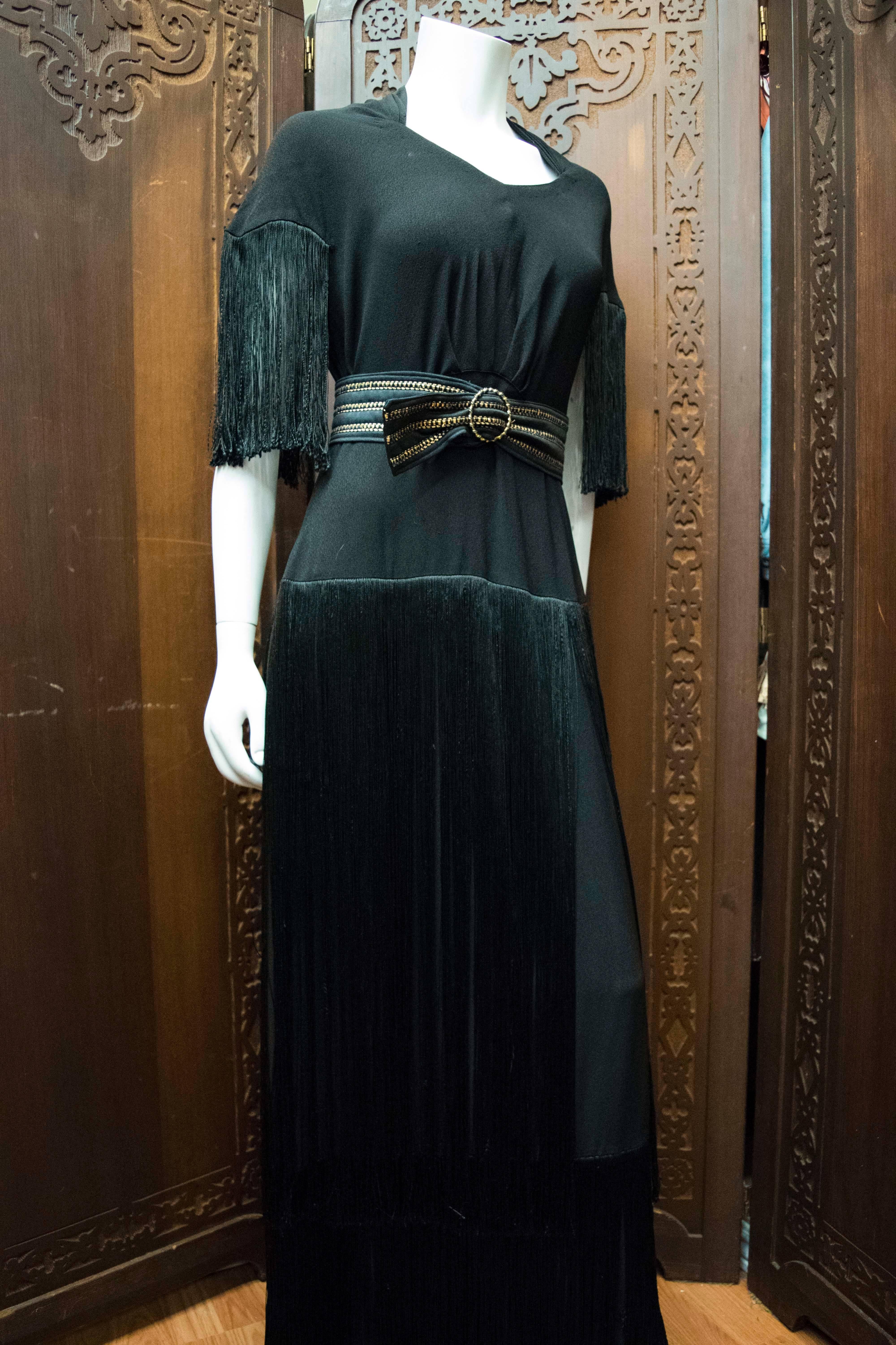 1940s Fringed Evening Dress

A completely wearable size, this dress boasts very long layered silk fringe skirt and silk fringe sleeves. Comes with black and gold belt. 

B 42
W 35
H 42
L 60