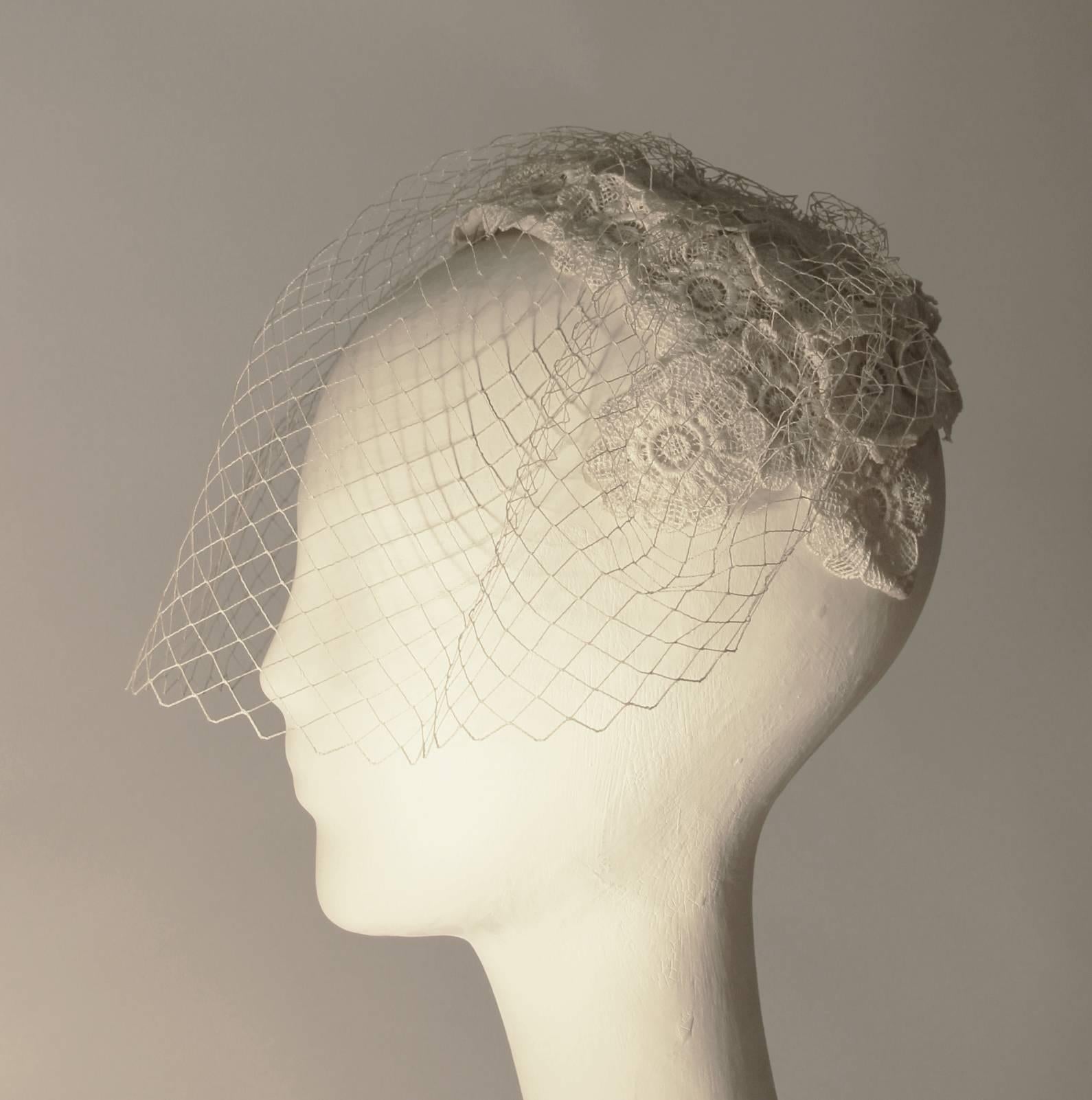 1950s white bridal and/or cocktail hat adorned with crochet style lace floral motif. Original veil. Excellent condition. 

