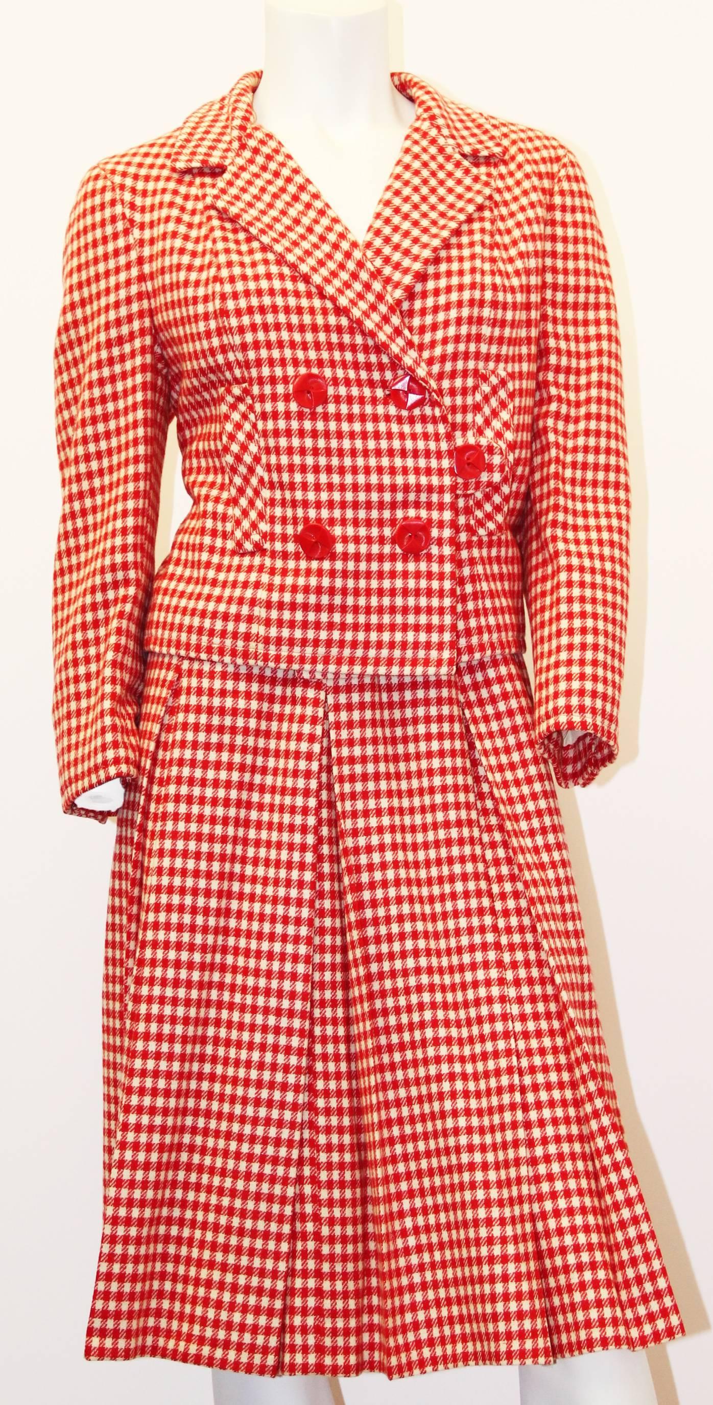 costume jupe double boutonnage en laine à carreaux rouge et crème I.MAGNIN & Co. des années 60. Cette veste entièrement doublée est dotée d'une double poitrine et de fausses poches sur le devant. La jupe plissée (non doublée) se ferme par une